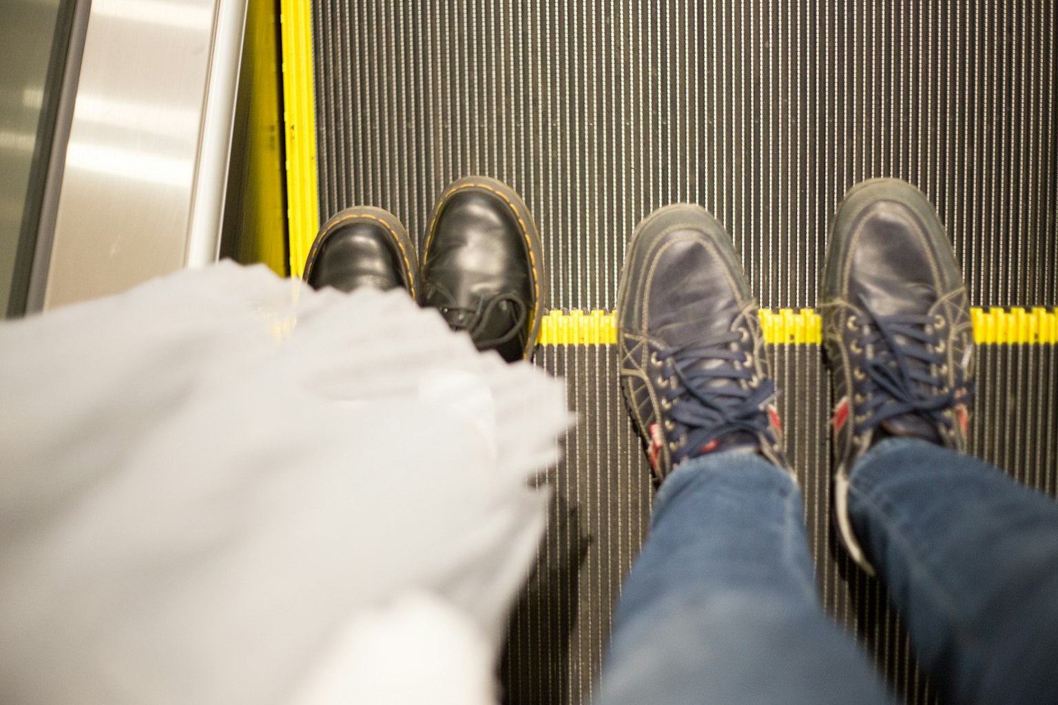 Pieds de deux personnes sur un escalator avec un parapluie