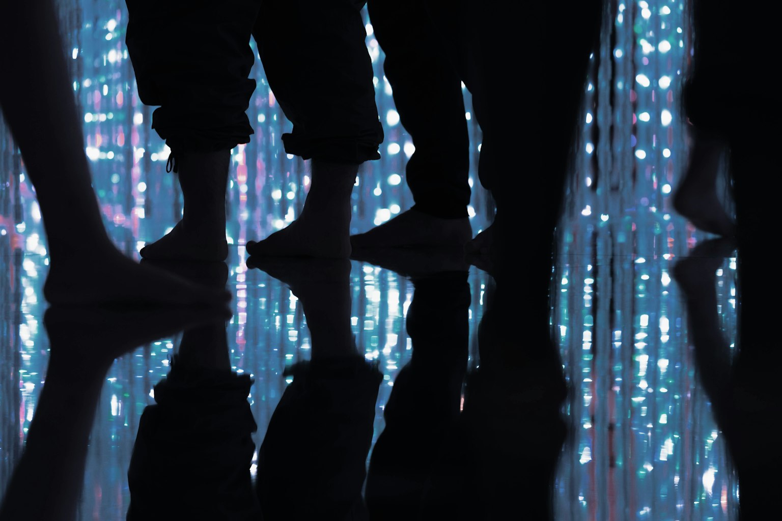 Des personnes debout au milieu d'une belle installation lumineuse avec des reflets de pieds
