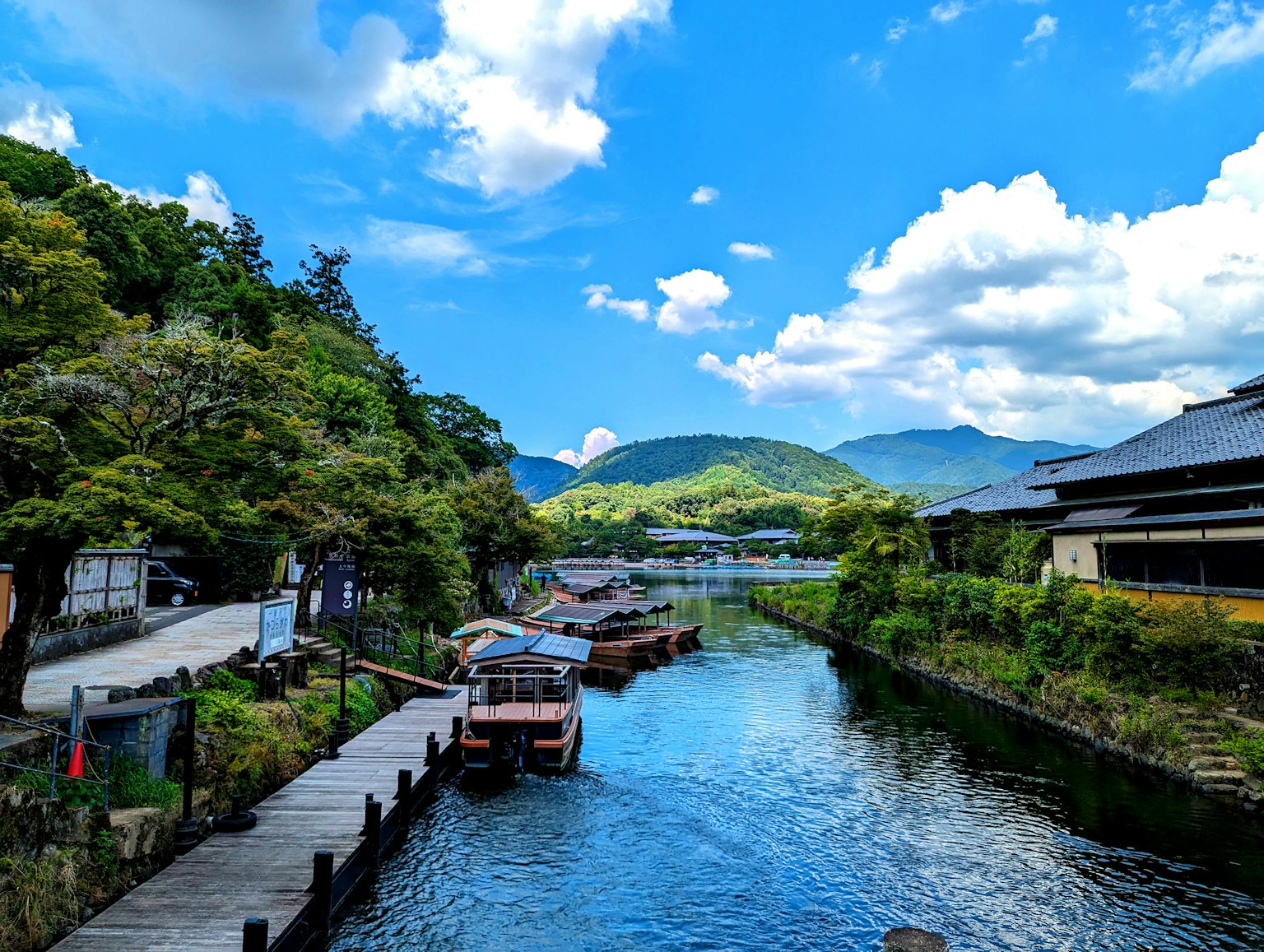 Scenic view of a river with boats and a blue sky surrounded by lush greenery