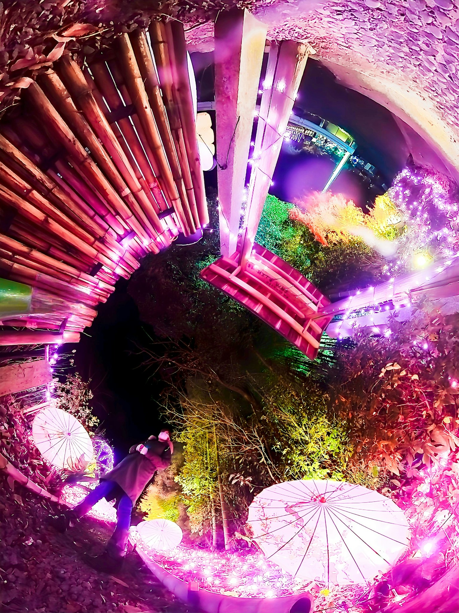 Una scena vibrante con strutture in bambù illuminate e ombrelli circondati da luci colorate