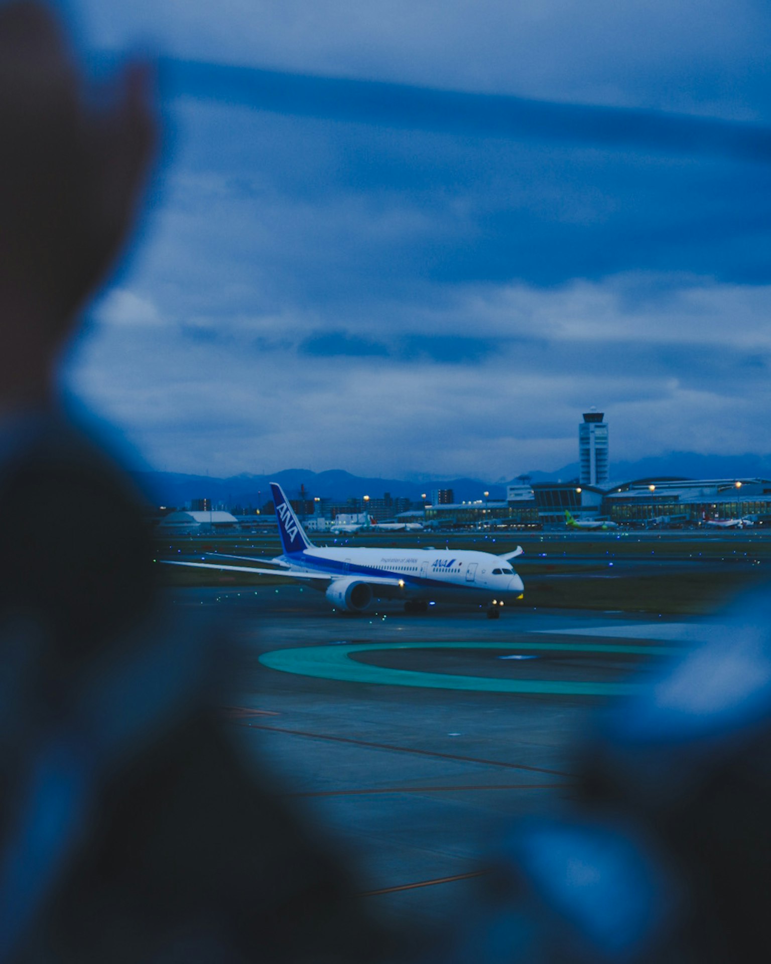 空港で離陸する飛行機の夜景 手前に人の手が見える