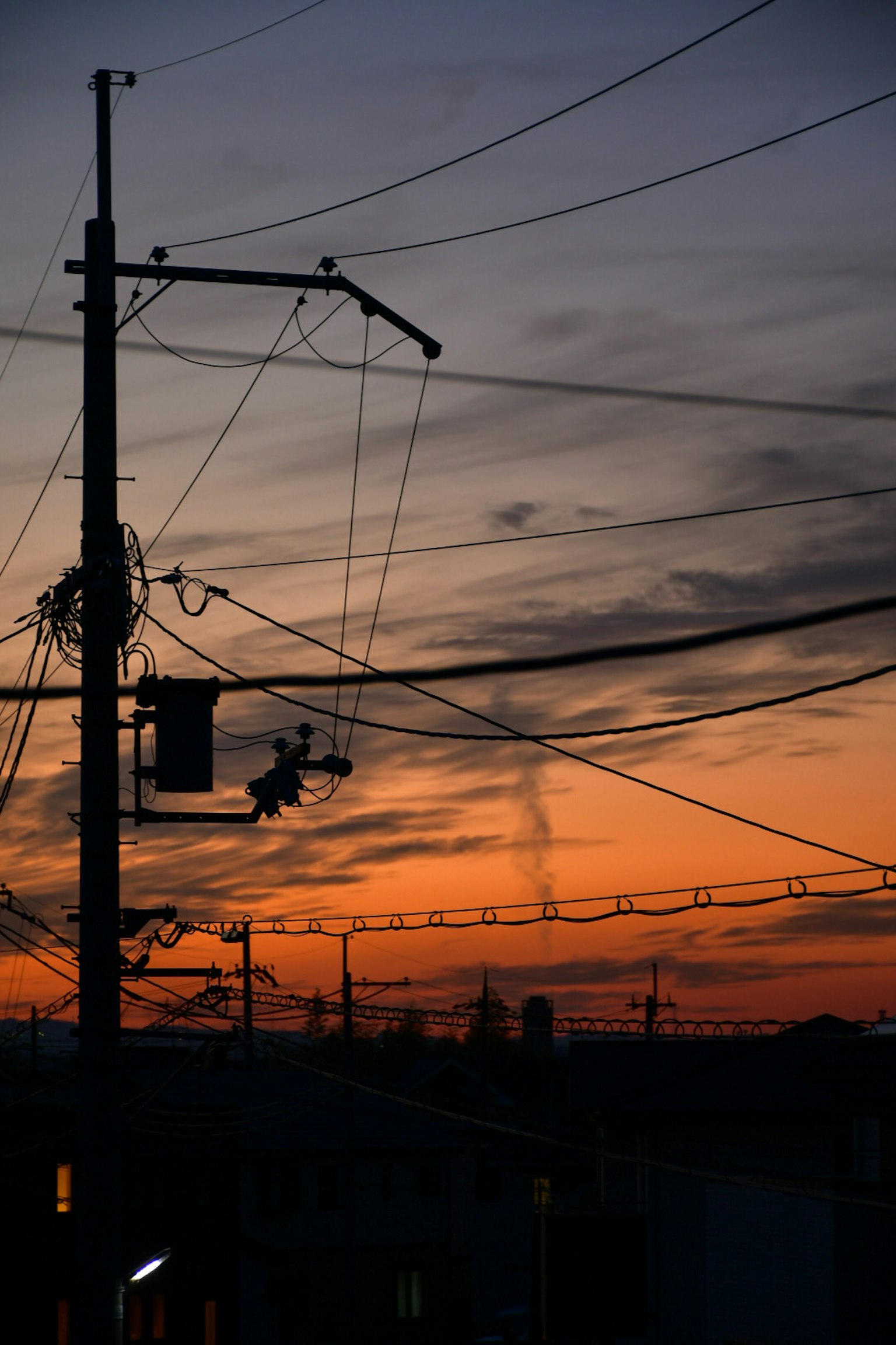 Silhouette eines Strommastes und von Stromleitungen vor einem Sonnenuntergangshimmel