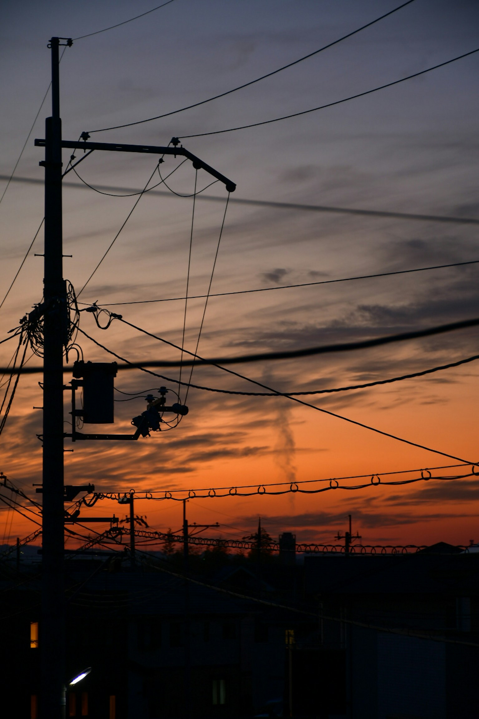 Silhouette di un palo della luce e linee elettriche contro un cielo al tramonto