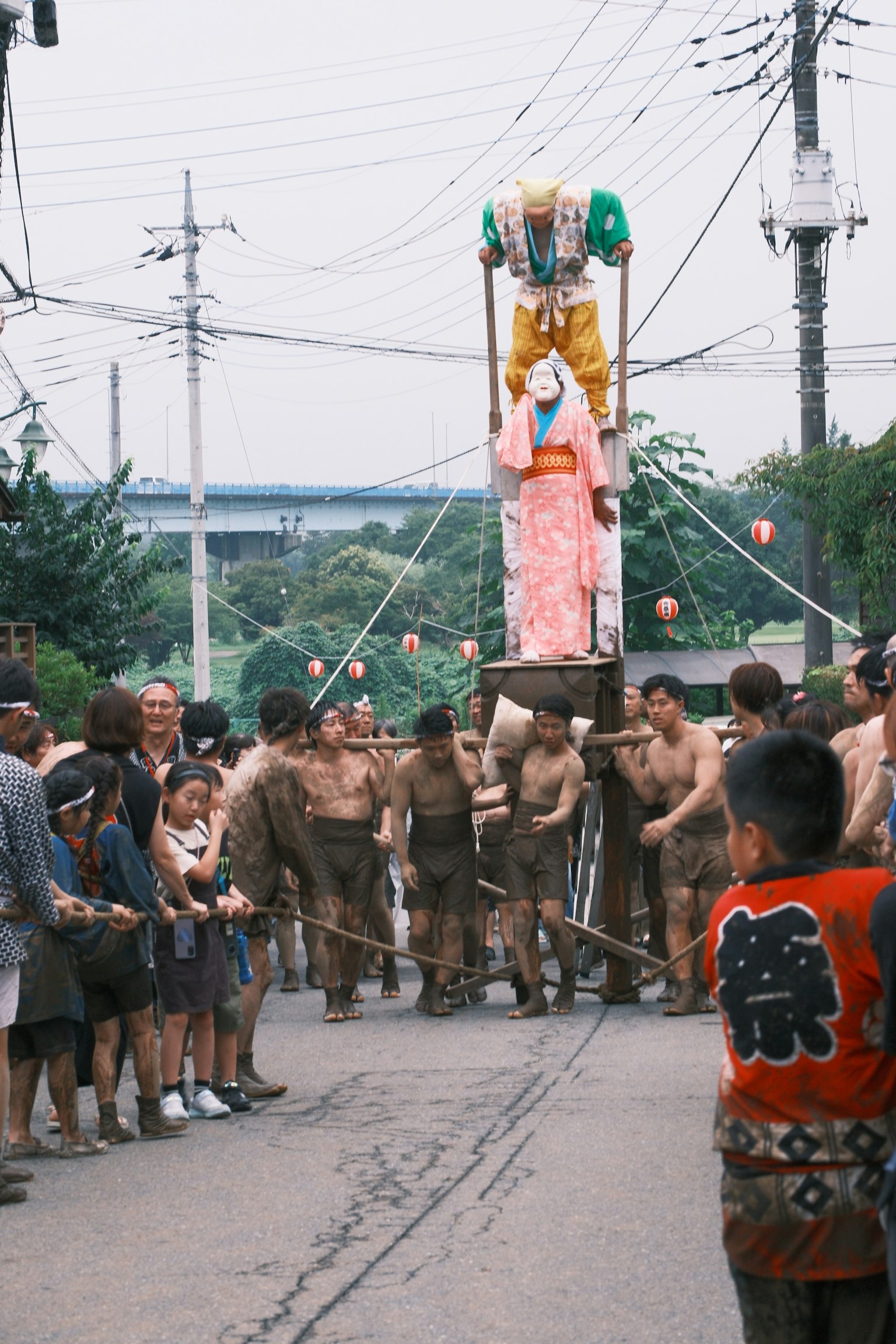 Men in traditional attire carrying a portable shrine during a festival with onlookers