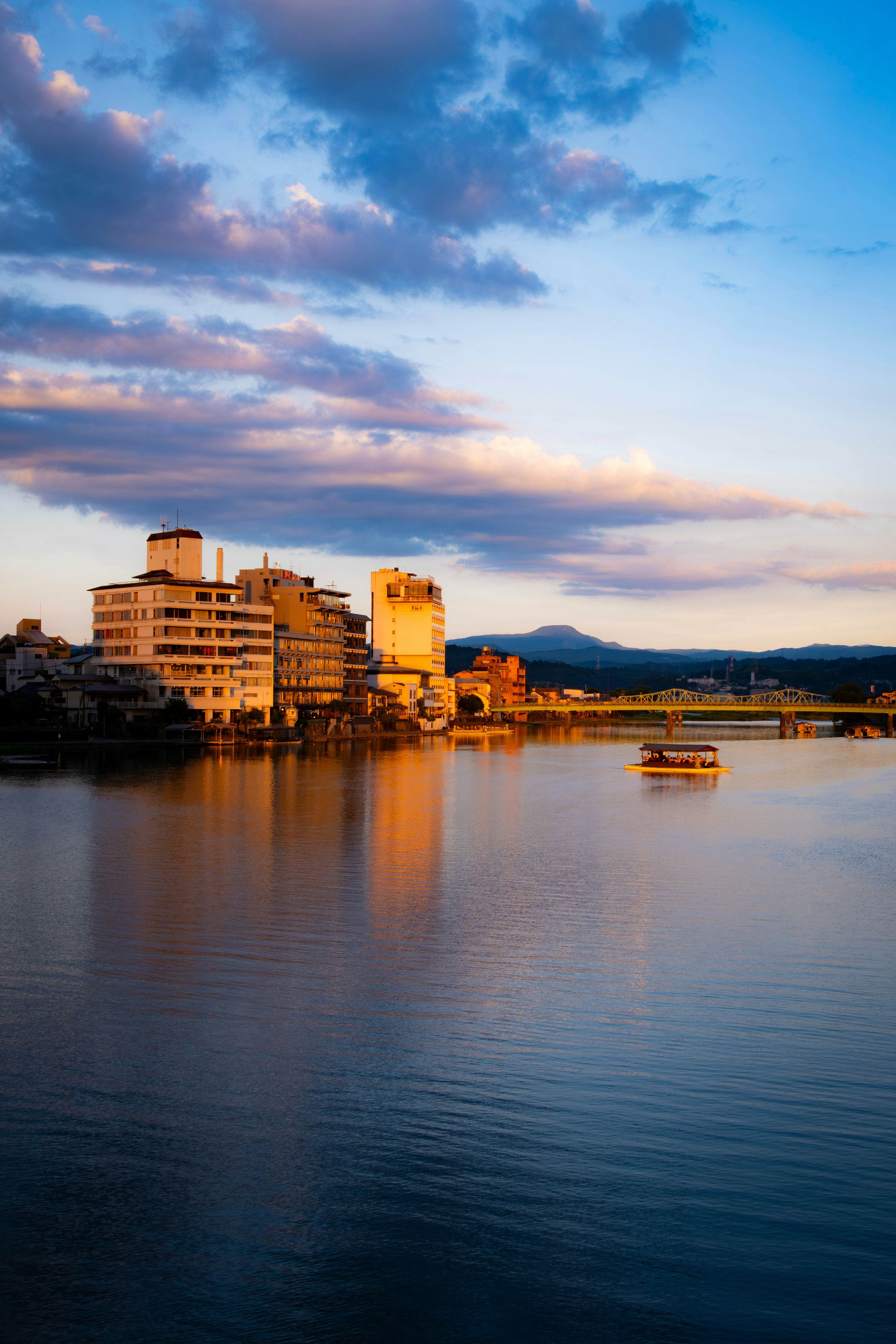 夏の河川敷から望む夕暮れの水面と街並み