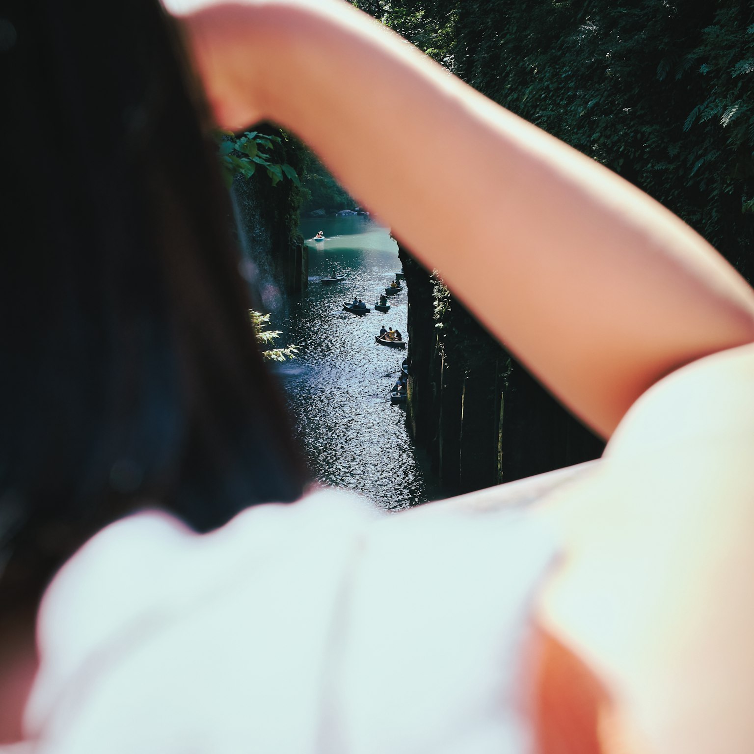 Pemandangan belakang seorang wanita yang mengamati sungai dikelilingi pepohonan hijau