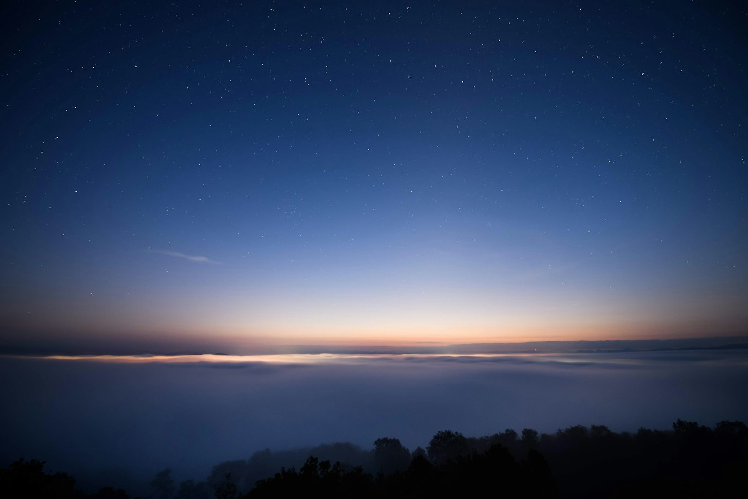 Bellissimo sorgere del sole su un mare di nuvole con un cielo notturno blu e stelle