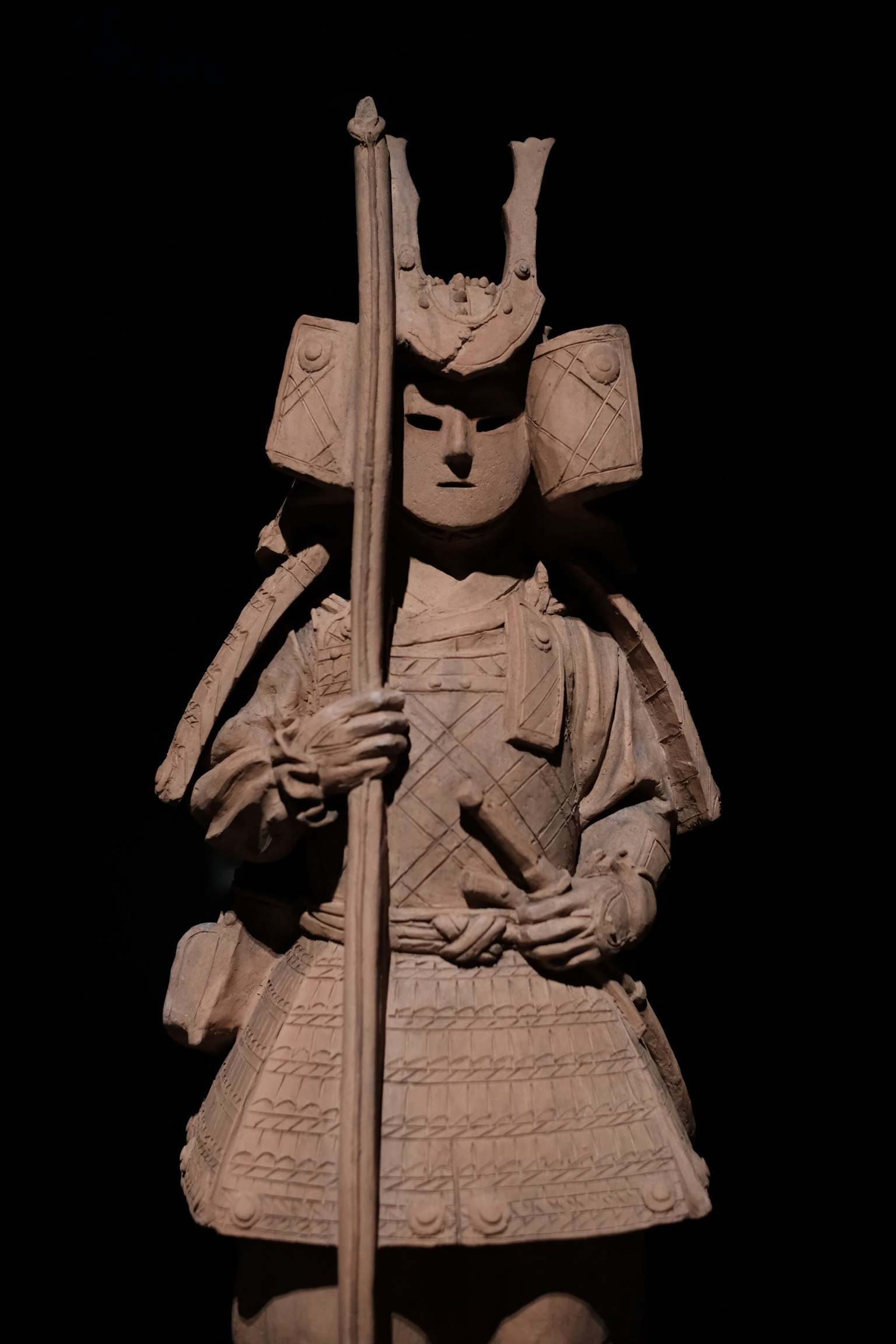 Una statua di samurai in piedi contro uno sfondo scuro