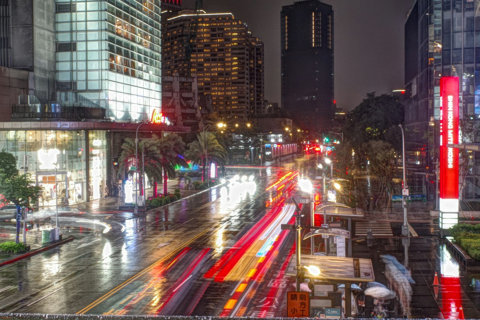夜の都市風景 雨に濡れた道路と流れる車のライト 高層ビルが立ち並ぶ