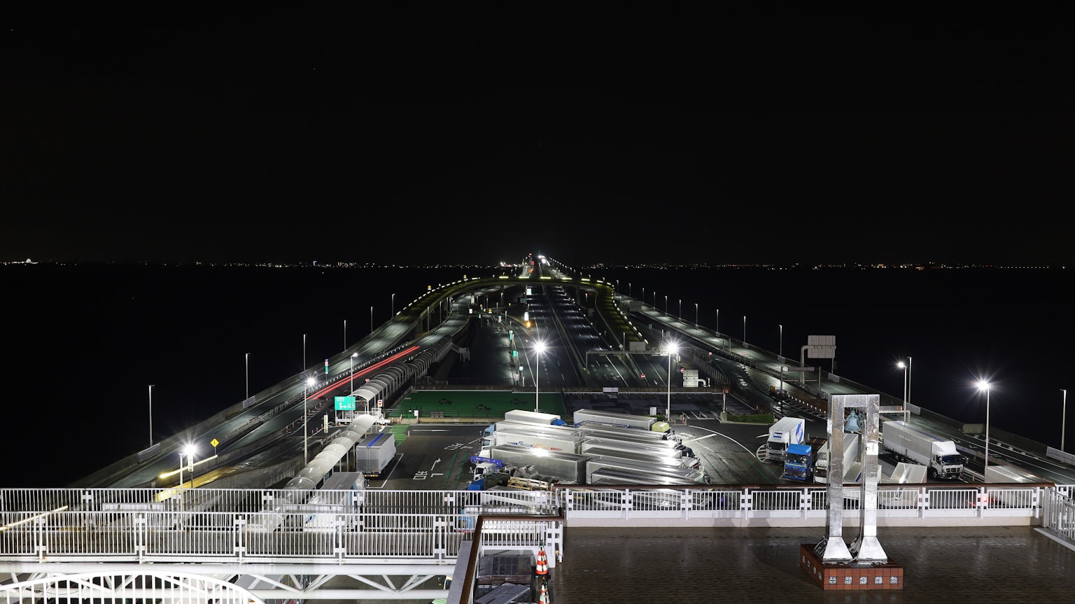 Vista nocturna de un muelle que se extiende hacia el mar luces de la ciudad brillando a lo lejos