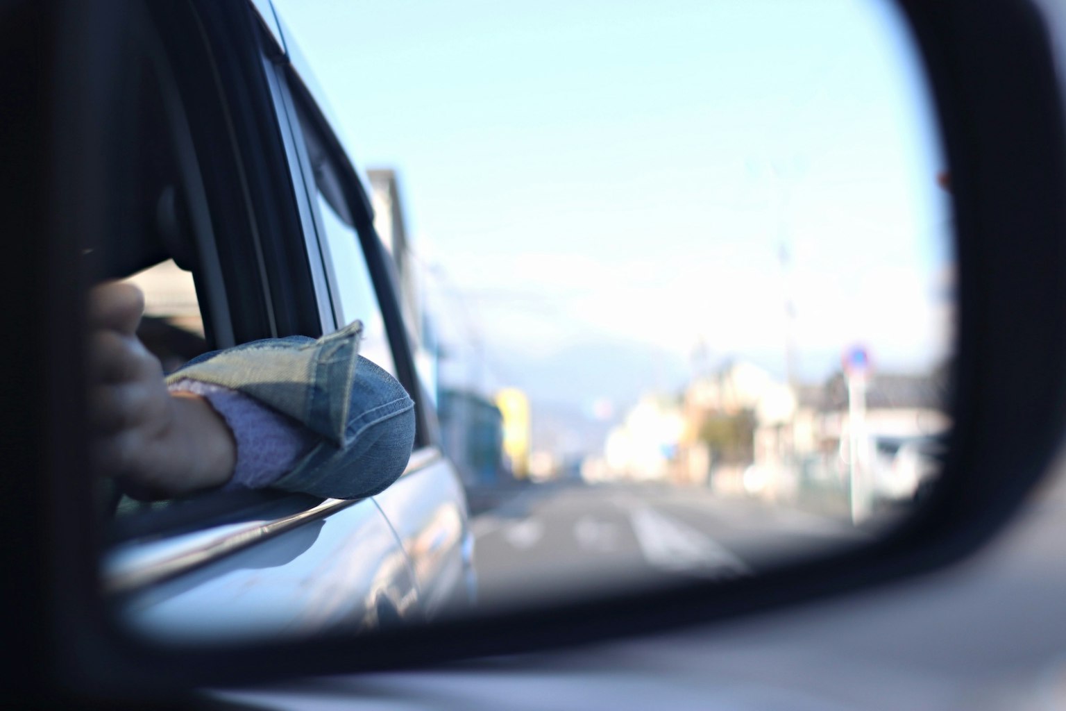 车窗外伸出手的反射，背景是道路