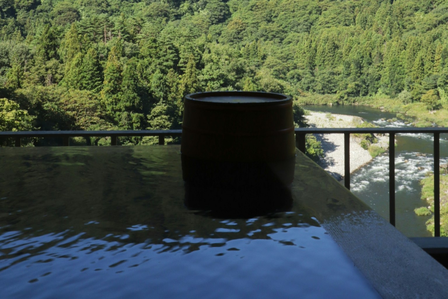 Tina de aguas termales con vista al río y vegetación exuberante