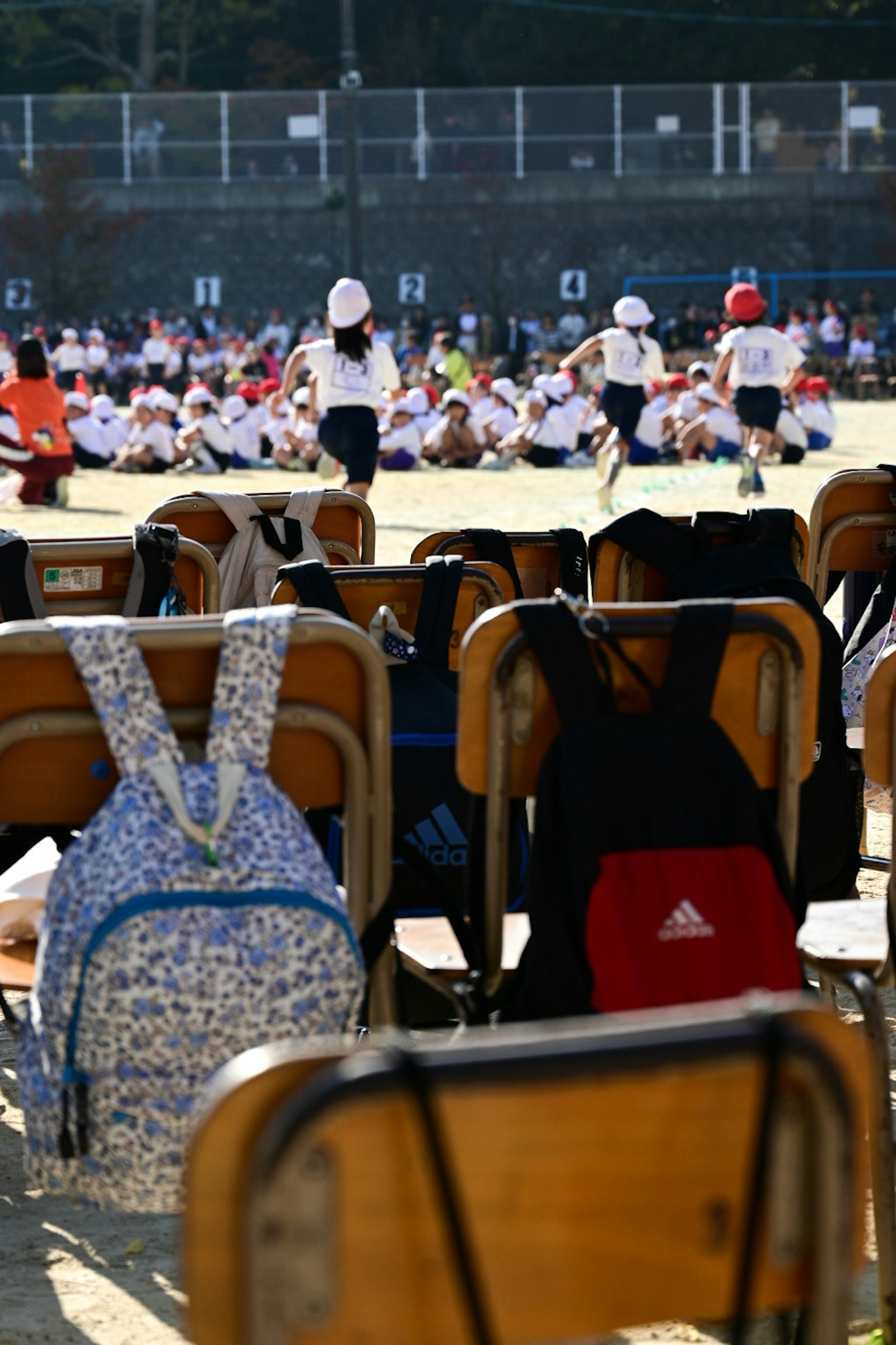 運動会のために並べられた椅子とバックパックが見える風景