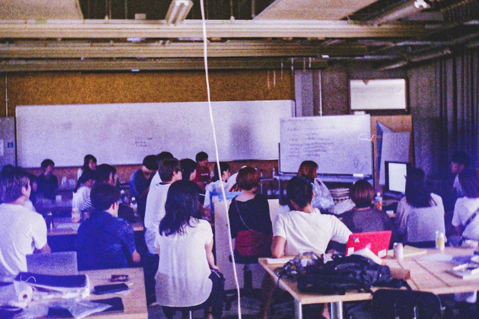 会議室でホワイトボードの前に集まる人々のオフィス風景