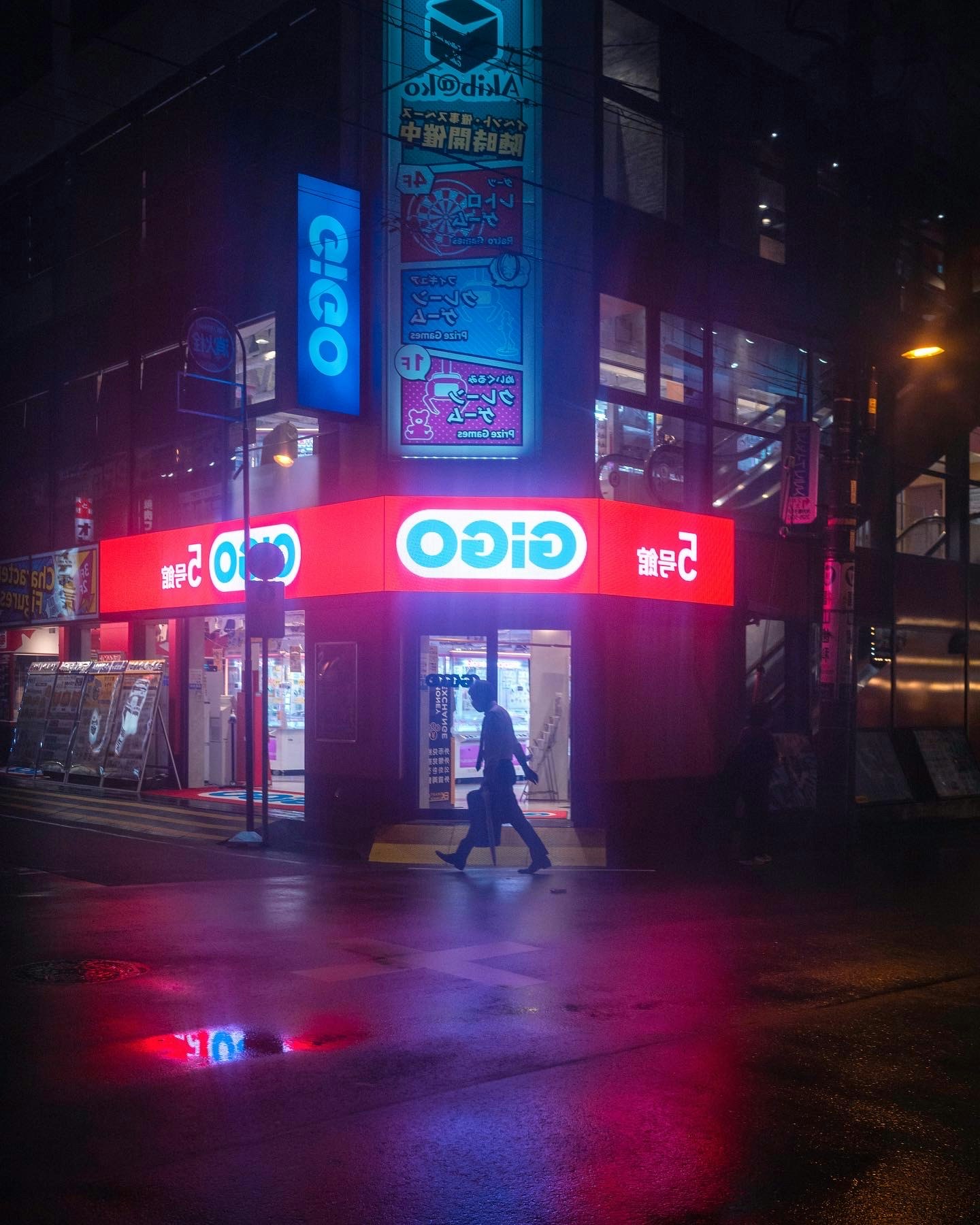 ネオン看板が並ぶ夜の路地のコンビニ前
