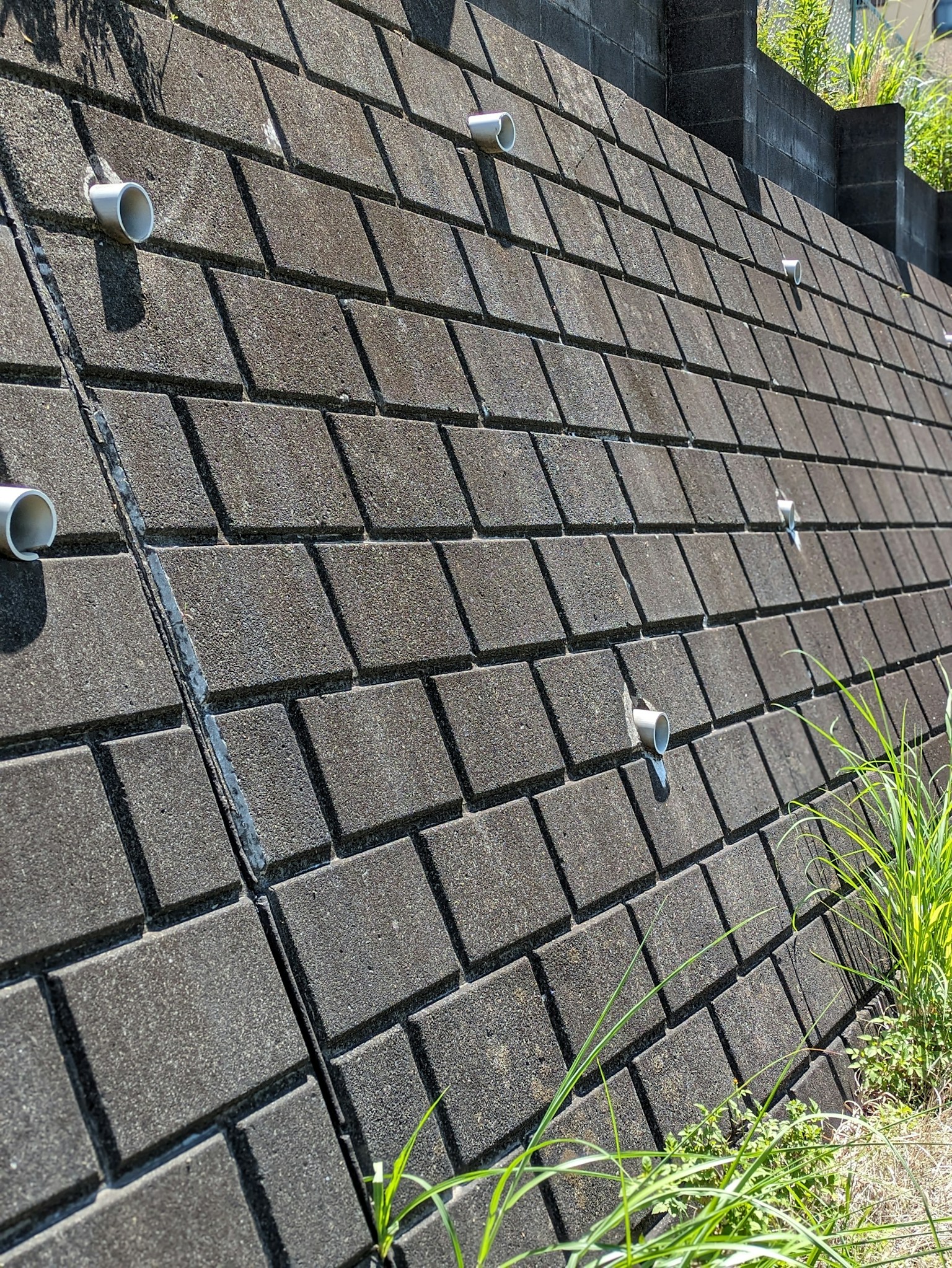 Black tiles arranged on a sloped surface with grass
