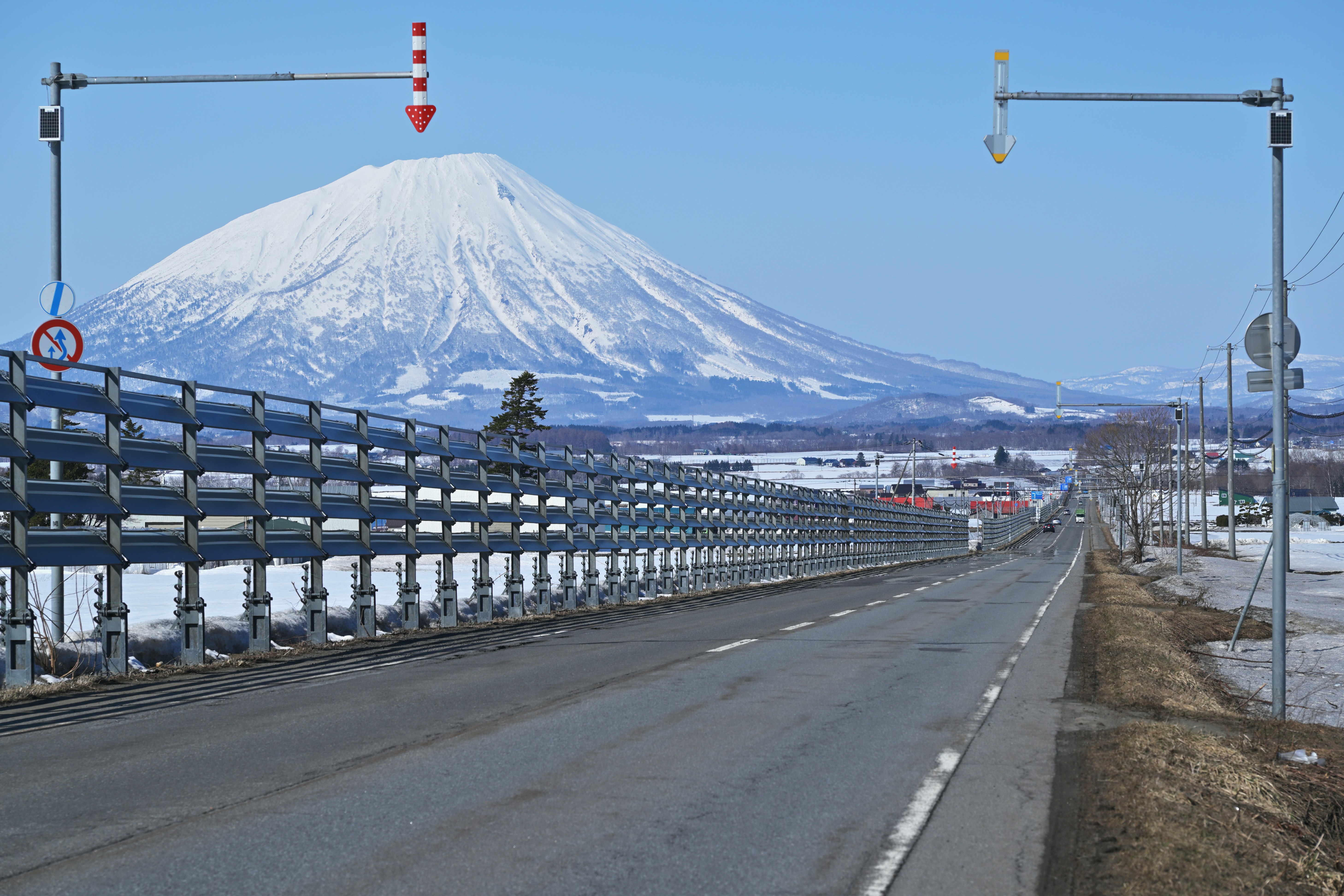 羊蹄山を望む直線の道路と並ぶフェンス