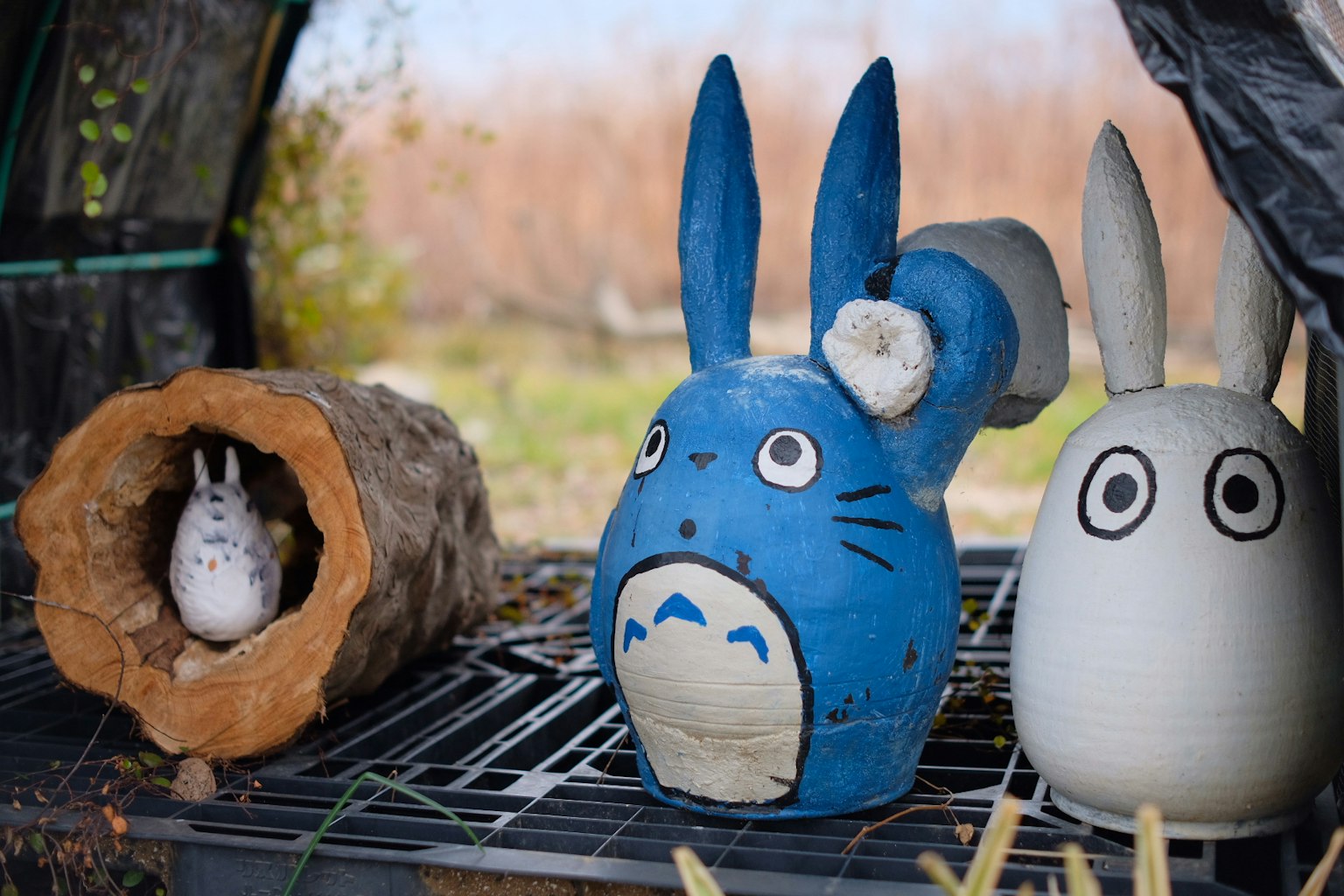 Eine blaue Totoro-Keramikfigur und eine weiße Hasenfigur zusammen ausgestellt