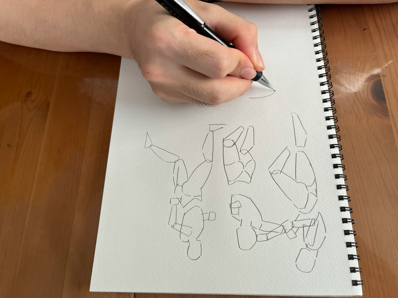 A person sketching on a blank page with unfinished drawings