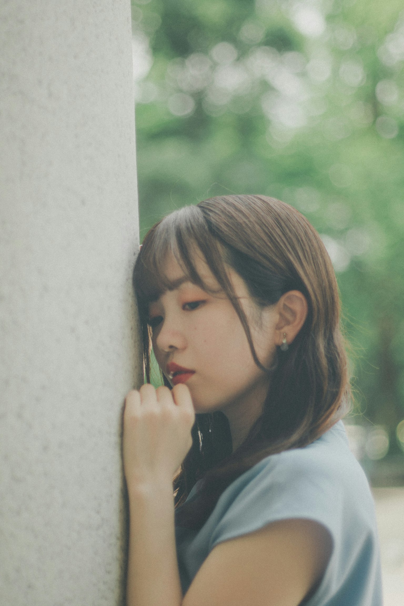 一位女性靠在柱子上，背景是寧靜的戶外環境