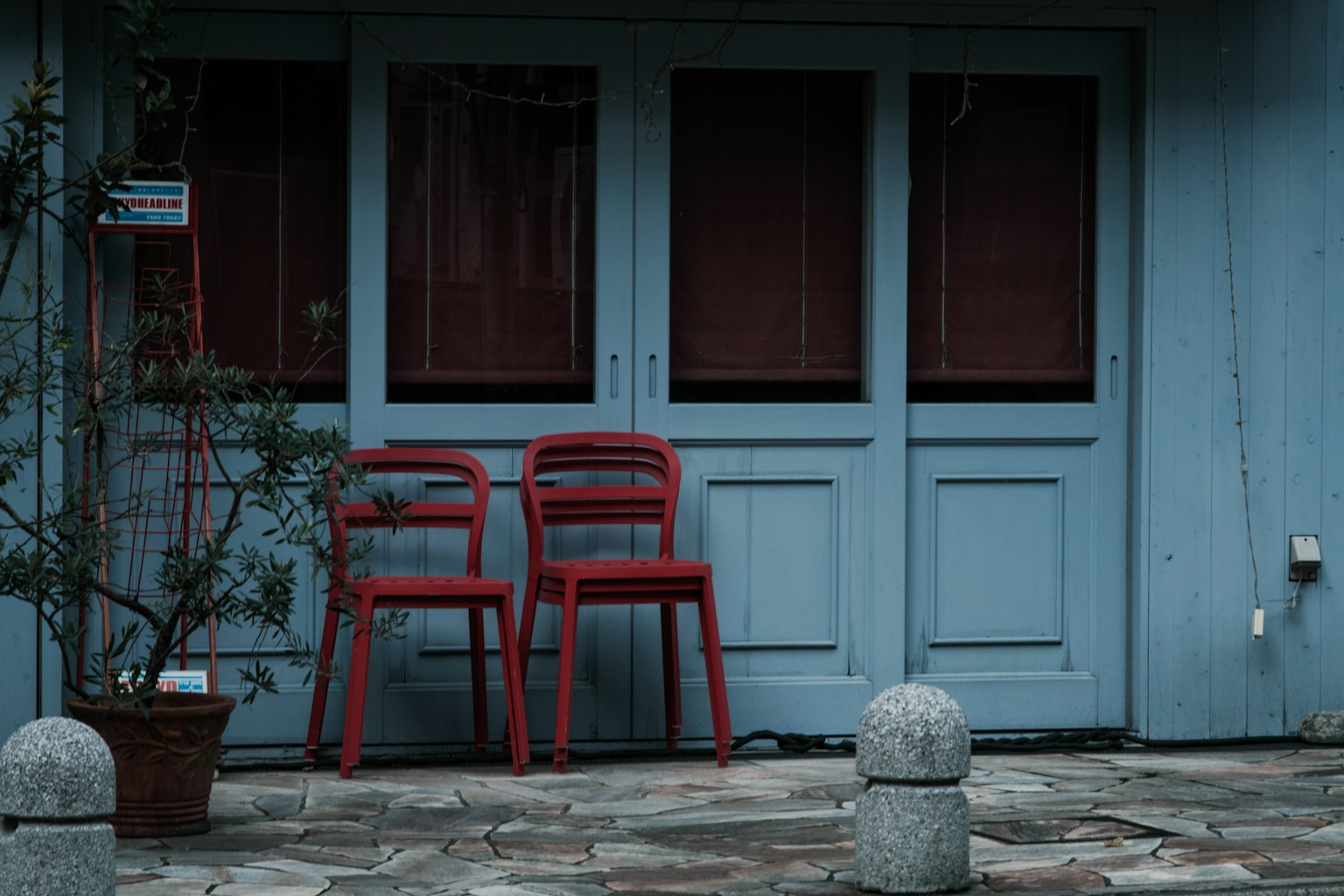 Two red chairs placed in front of a blue door