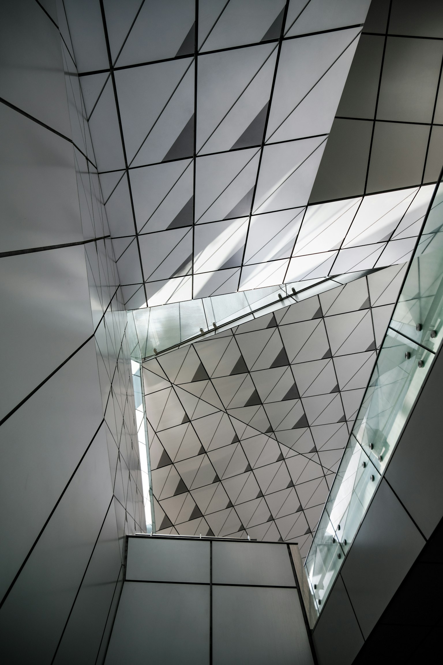 Interior de un edificio moderno con paredes blancas geométricas y reflejos de luz