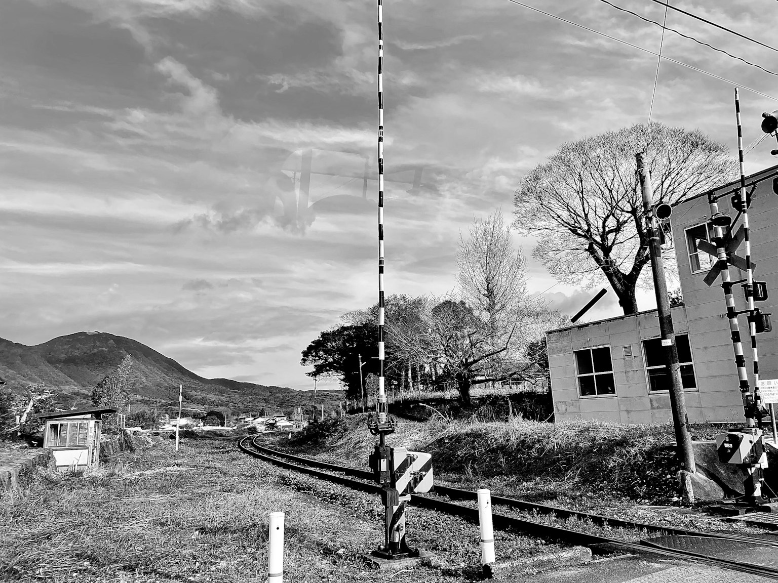 Image en noir et blanc d'un passage à niveau avec paysage environnant