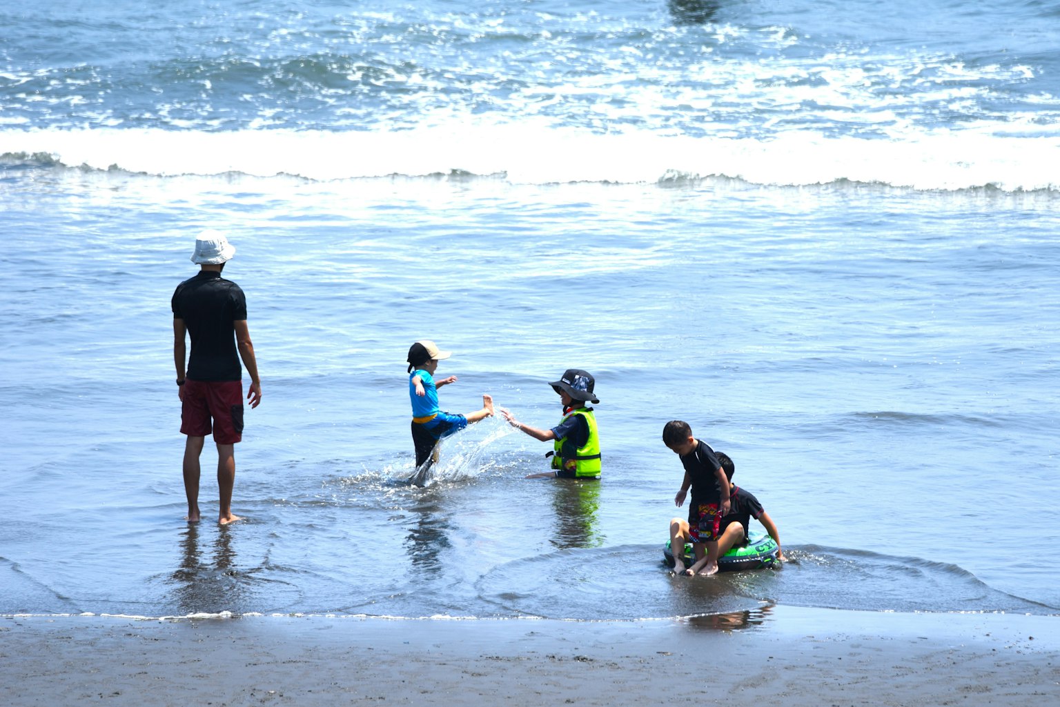 Children playing in the ocean with an adult silhouette