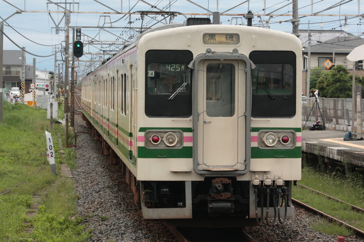 A green and white train stopped at a station