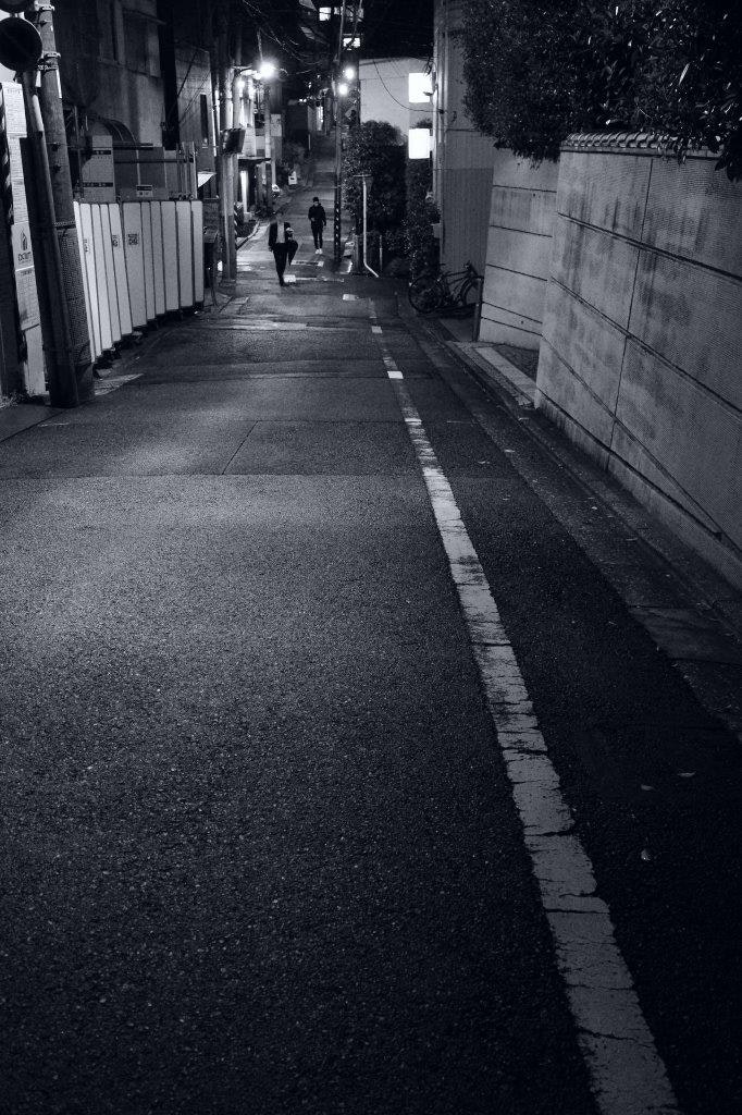 夜の路地に続く街灯と人影のある石畳の通り