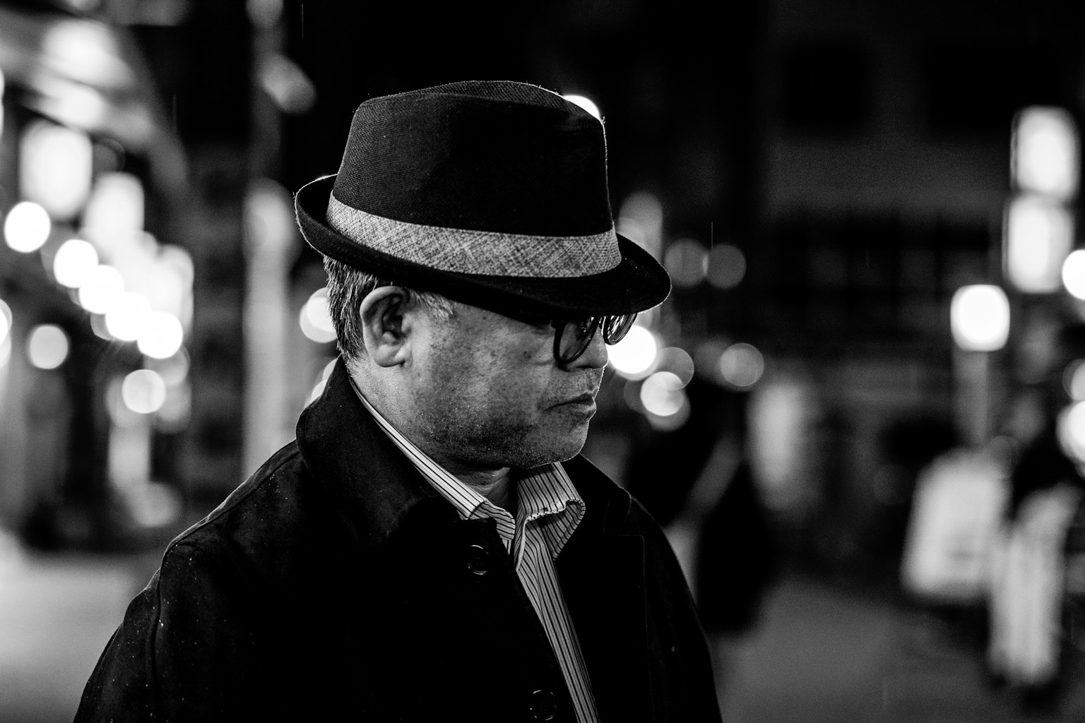 A man in a black hat is quietly pondering in the night streets