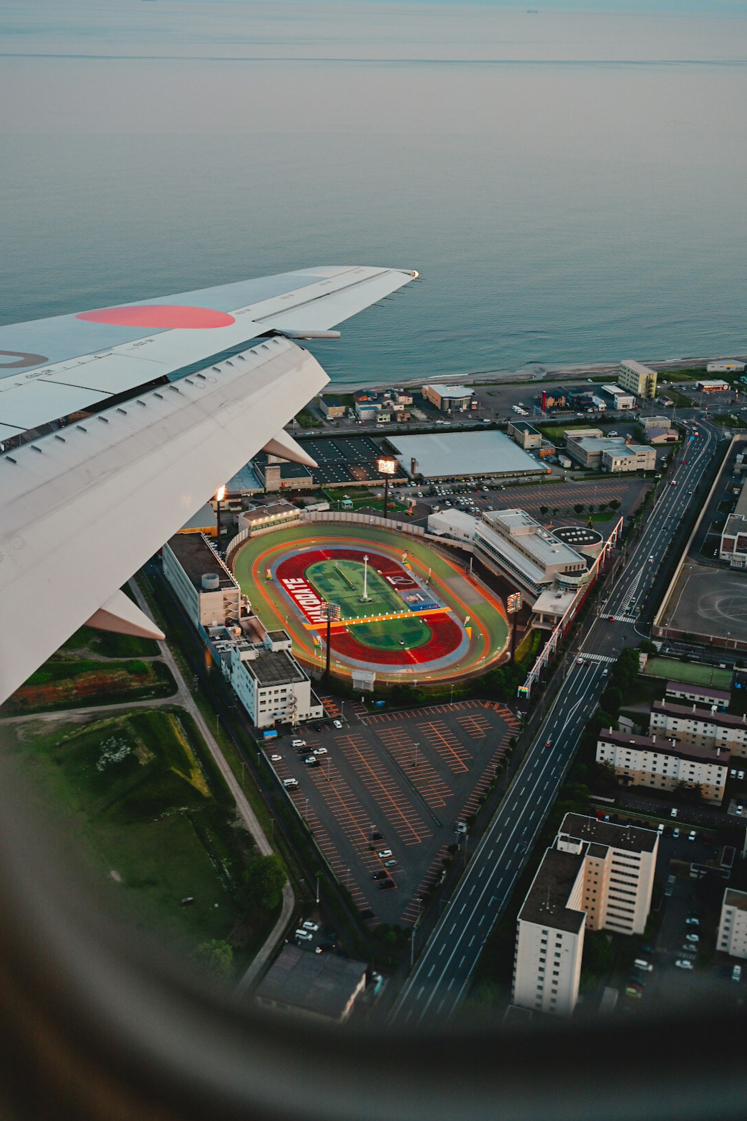 飛行機の翼から見た海とスタジアムの景色