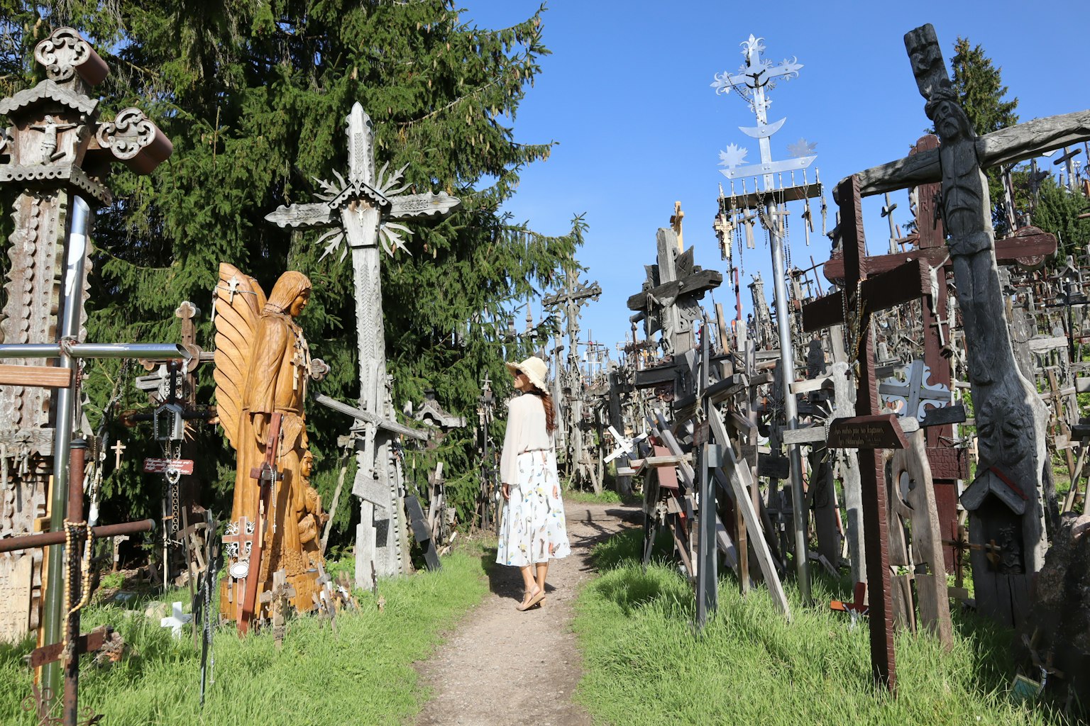 Una donna che cammina in un cimitero pieno di croci di legno e sculture