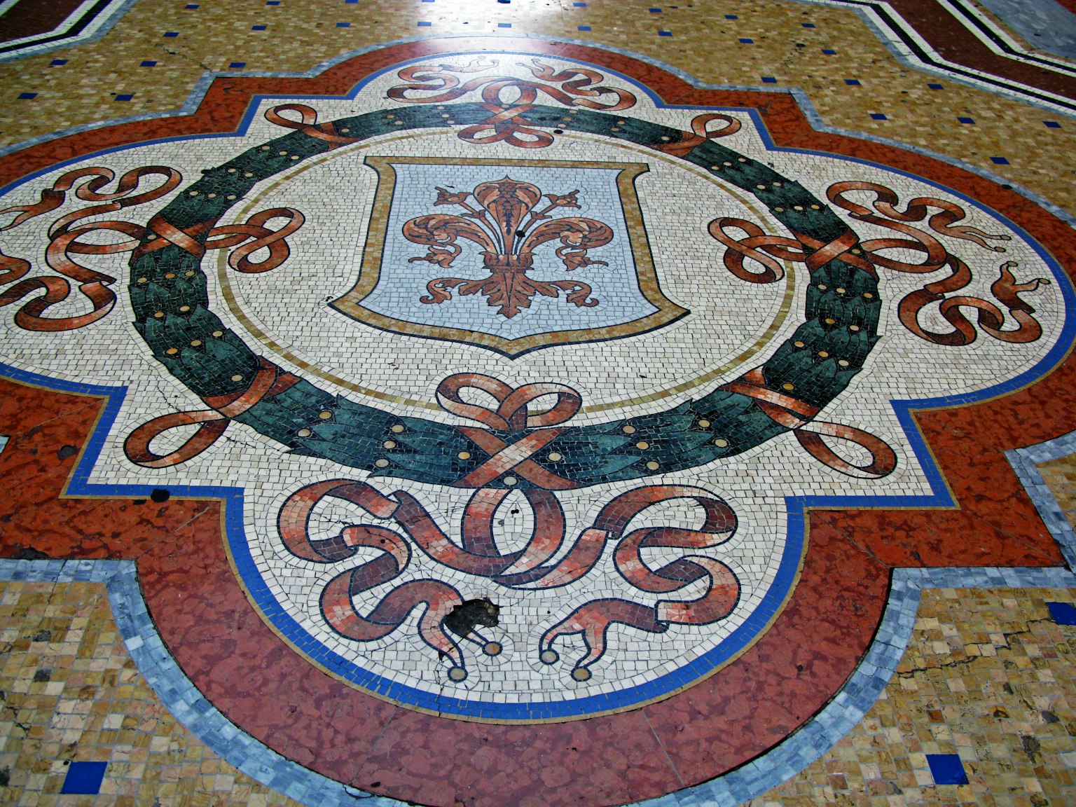 Diseño de piso de mosaico intrincado con un escudo central y patrones florales