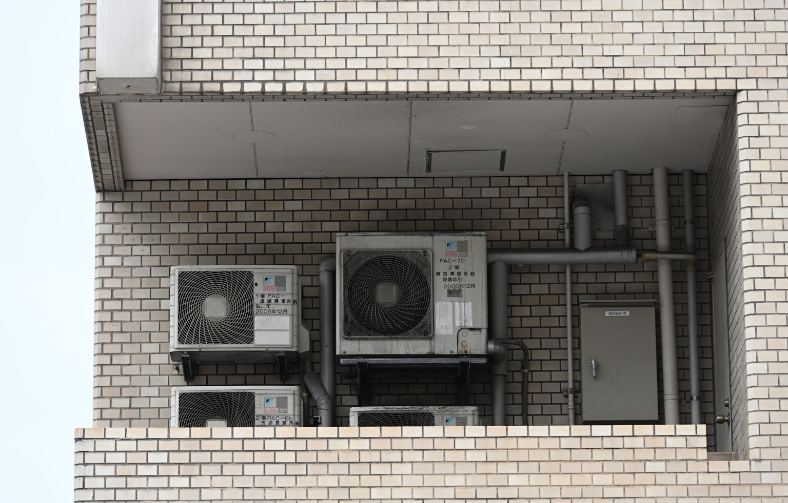 Unités de climatisation et tuyauterie sur un balcon d'immeuble