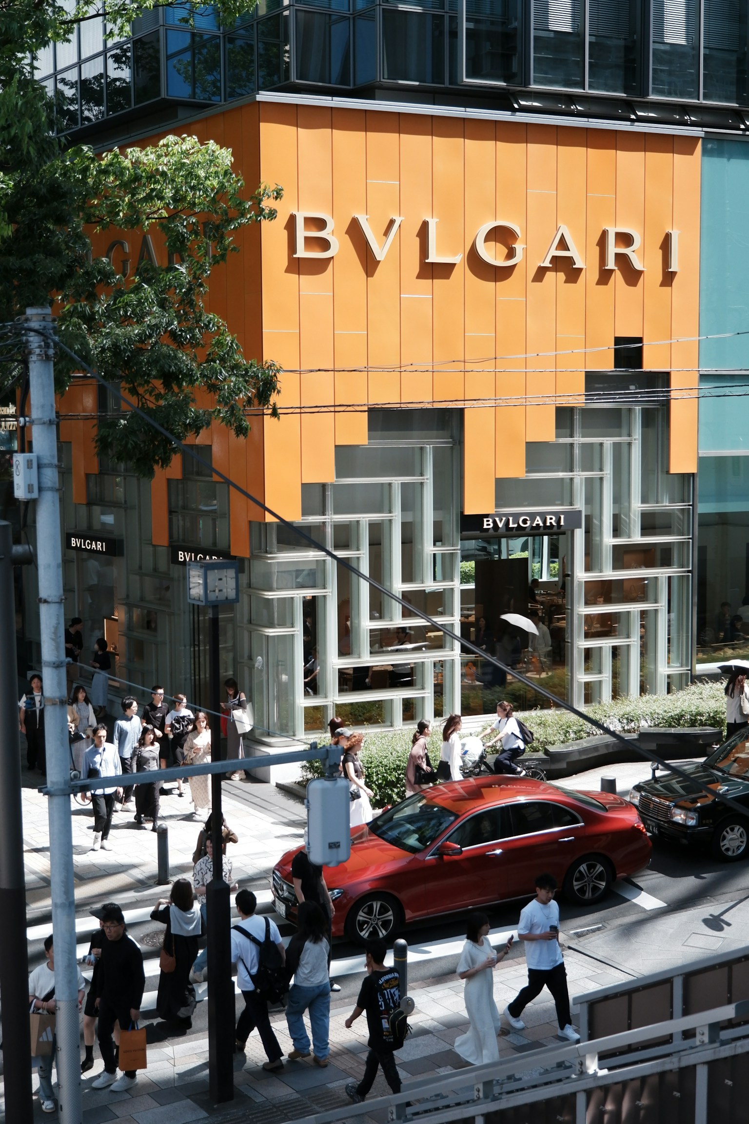 Street view featuring BVLGARI store with orange facade and pedestrians