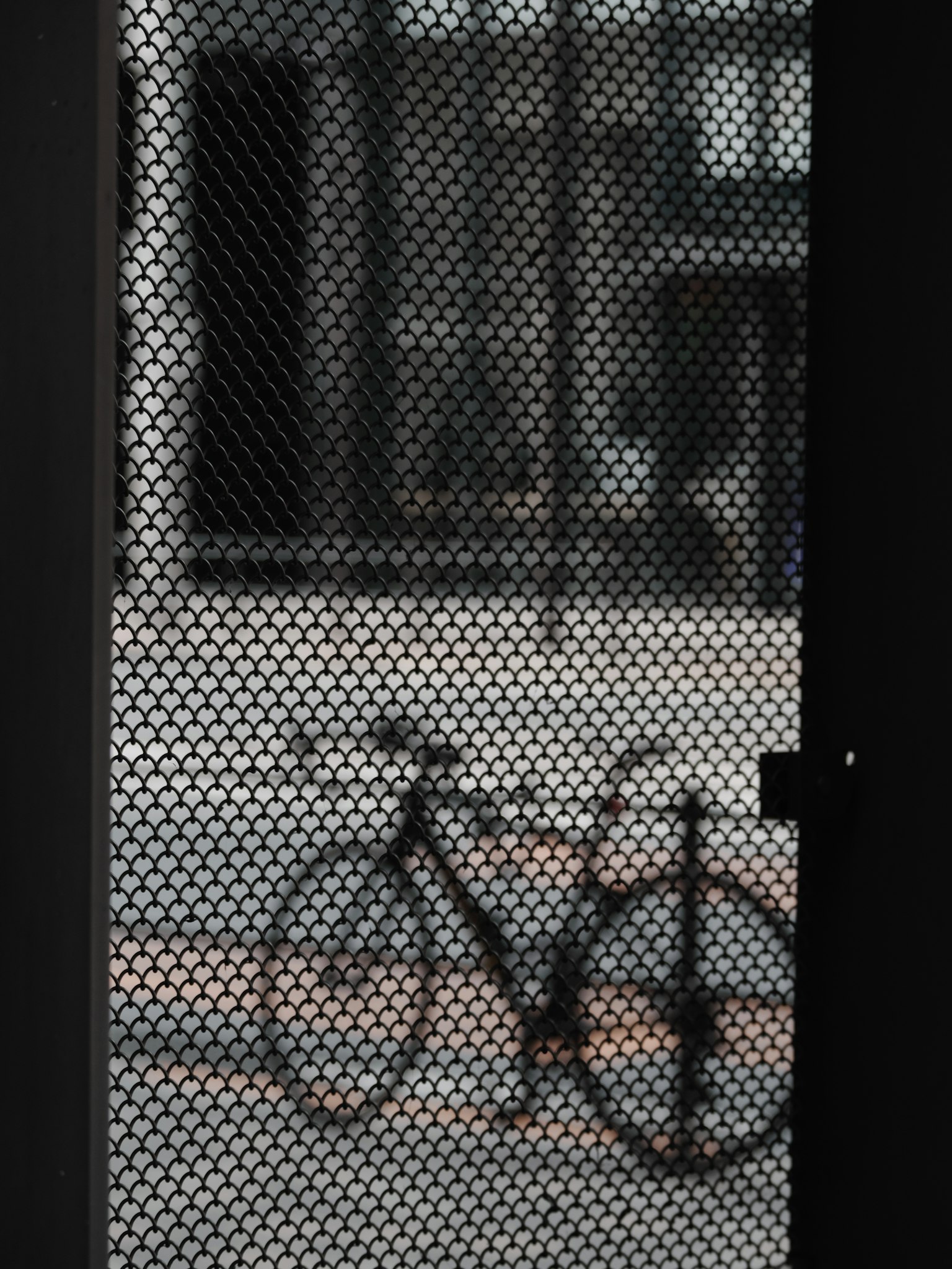 Bicicletta visibile attraverso una rete con sfondo urbano