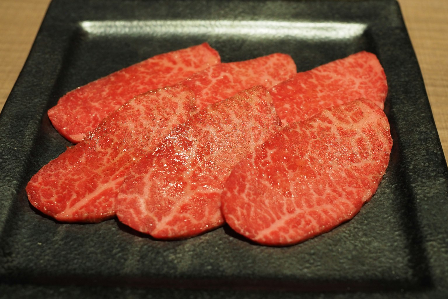 薄切的和牛肉放在黑色盤子上