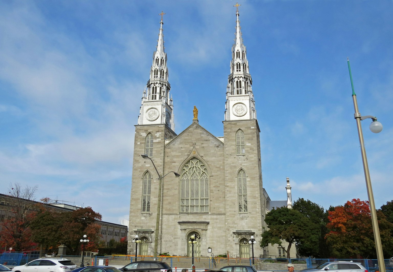 Façade d'une église en pierre avec des flèches blanches et des horloges