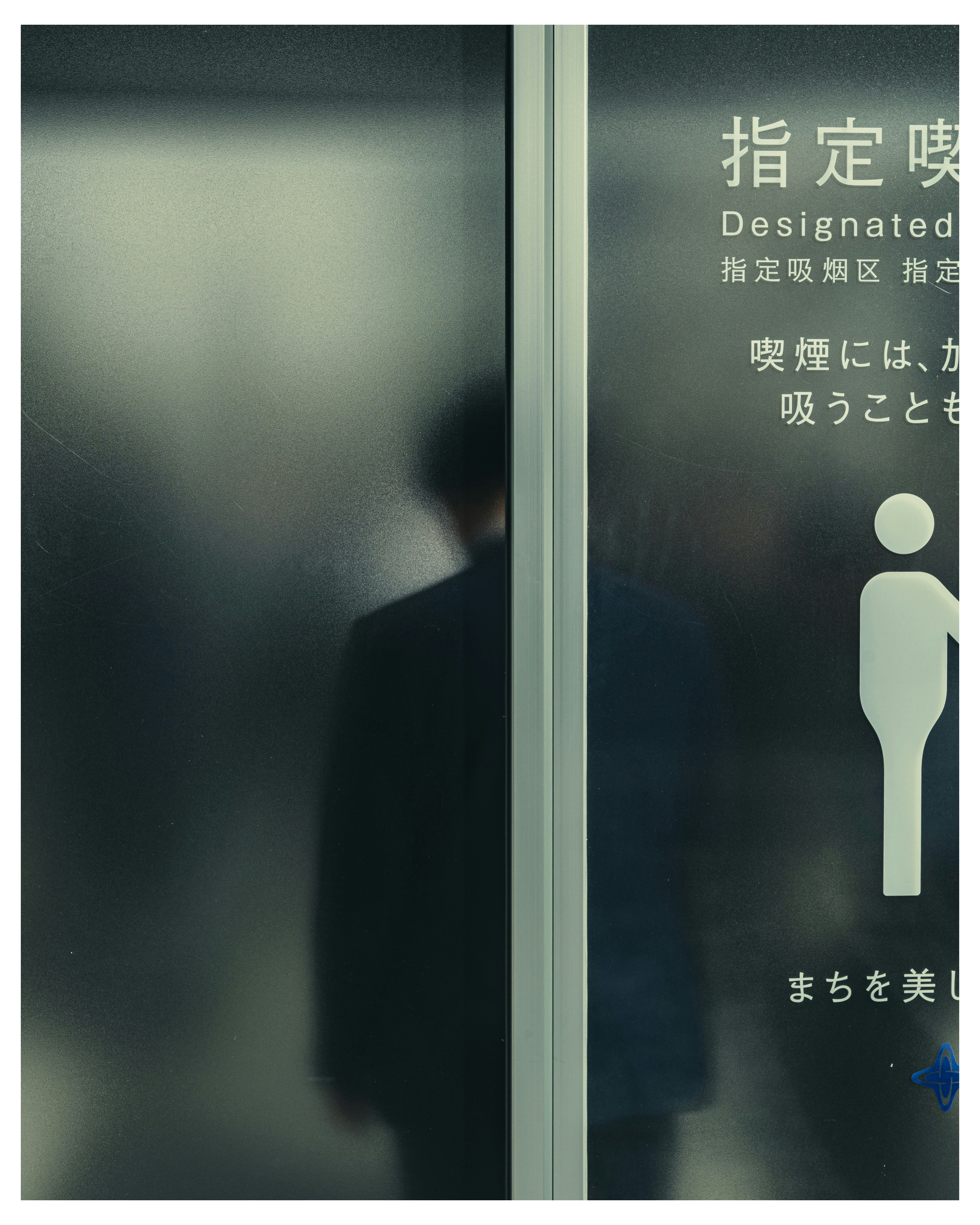 ガラス扉に映る人物のシルエットと注意書きの表示
