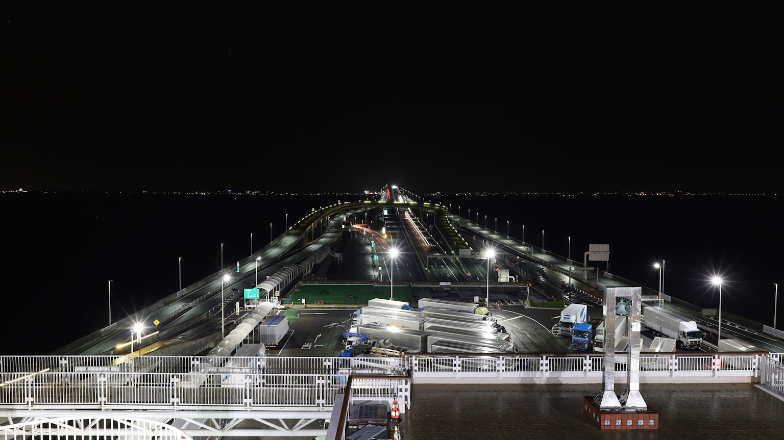 Una vista serena de un largo muelle por la noche con luces iluminando el camino