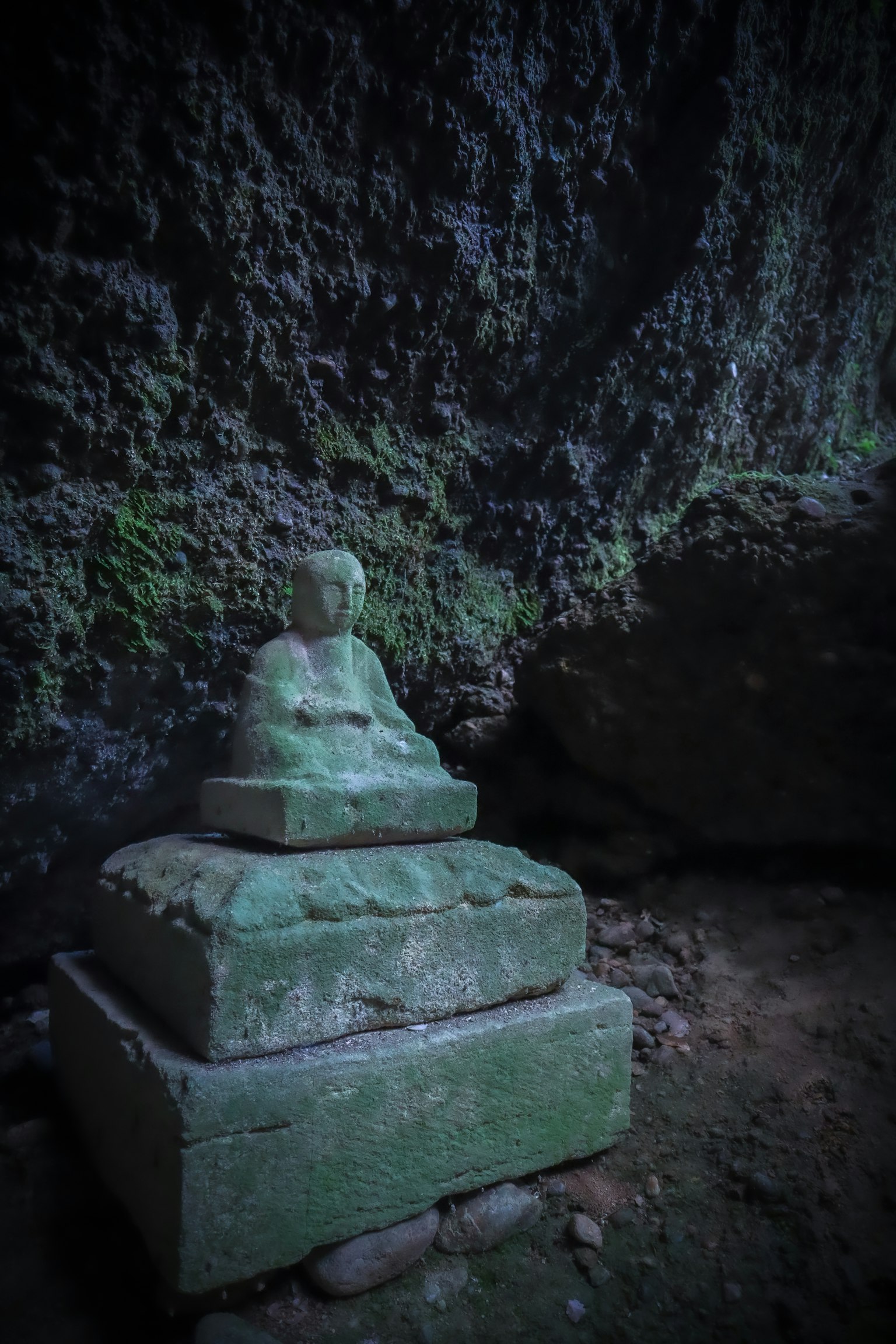Ancient Buddha statue inside a cave Sitting on a green stone pedestal