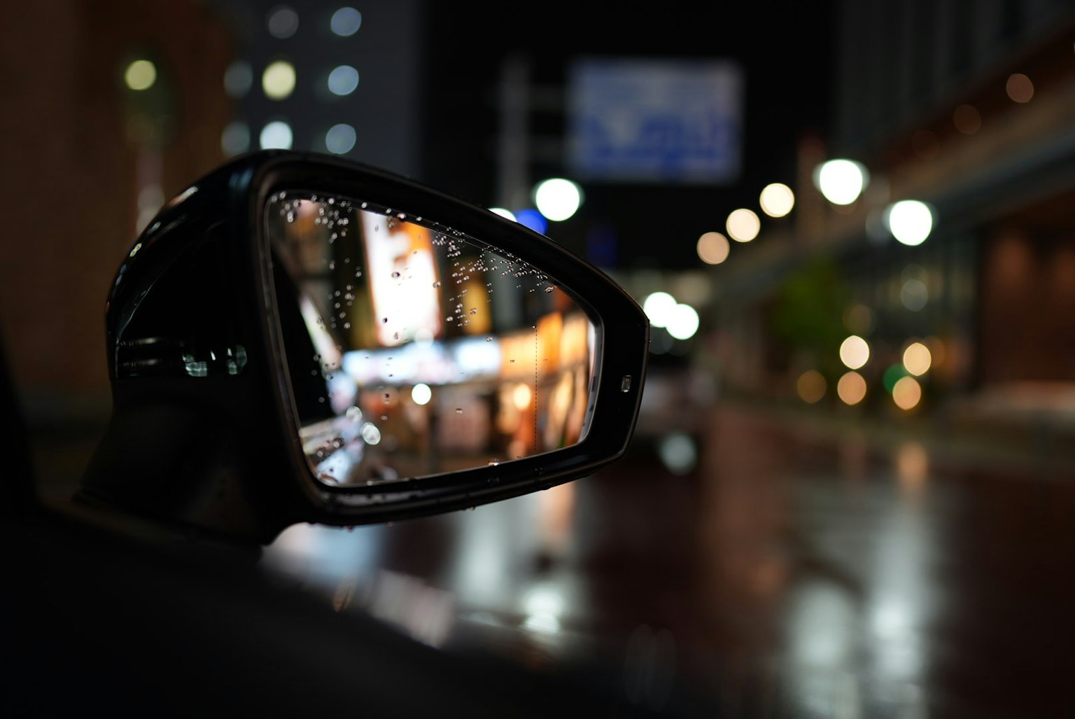 汽車側鏡反射夜晚城市燈光帶雨滴