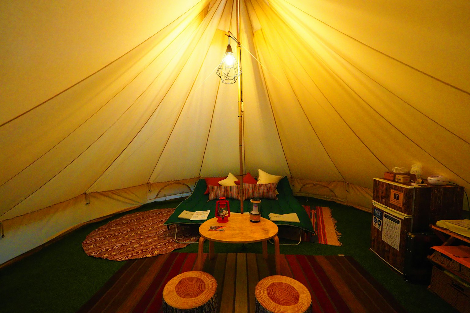 Interno accogliente di una tenda con illuminazione calda tappeti colorati e cuscini disposti