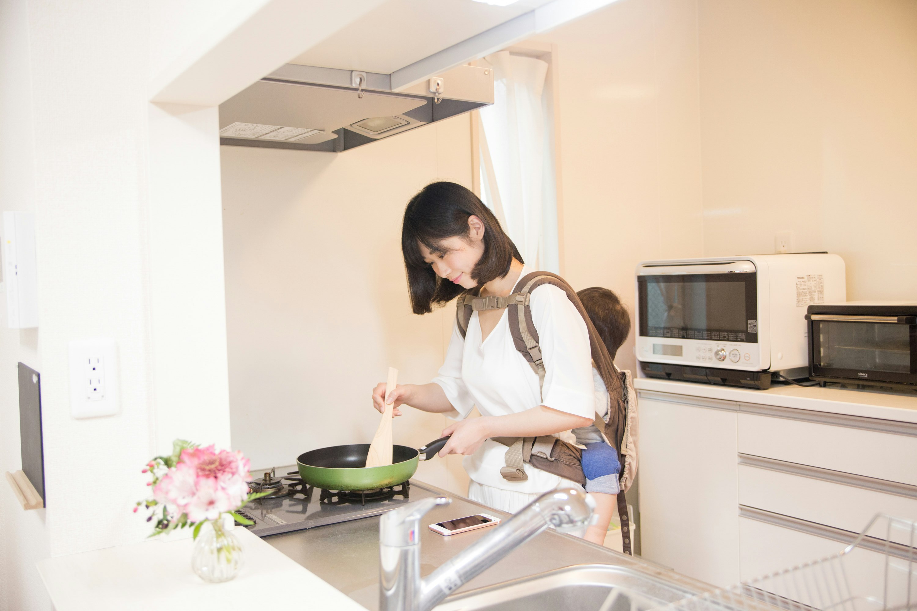 白いキッチンでフライパンを使う親子の料理風景