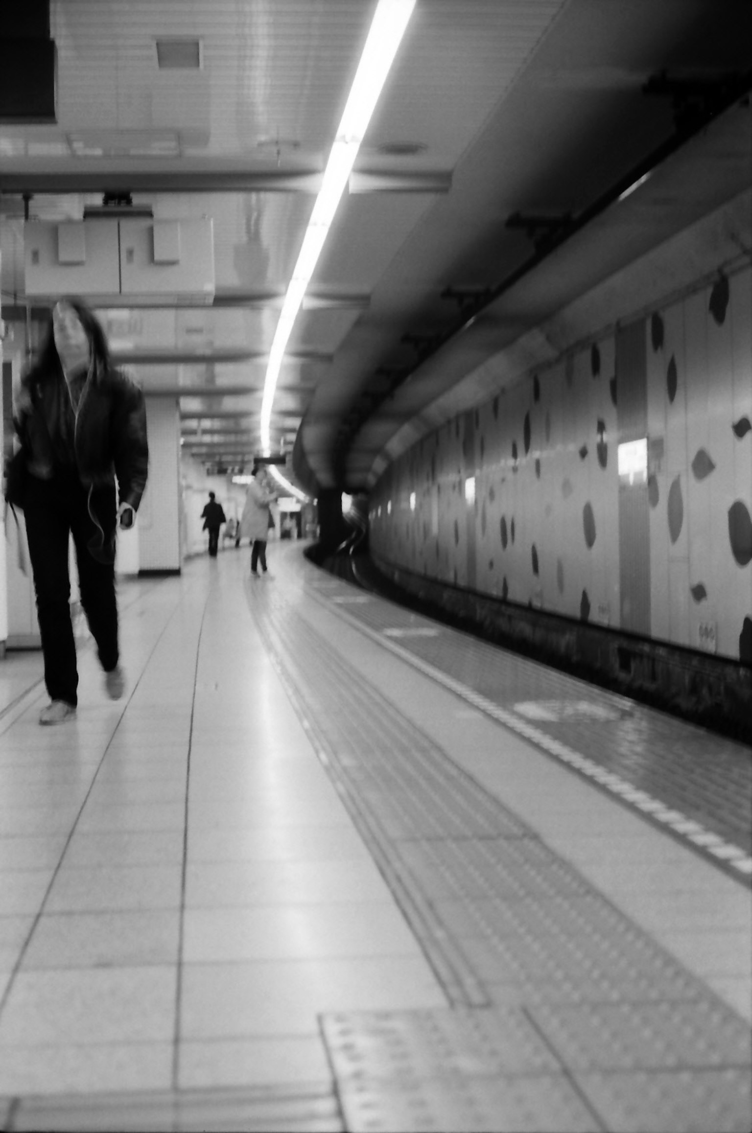 Corridoio della stazione della metropolitana in bianco e nero con persone che camminano e muro a pois