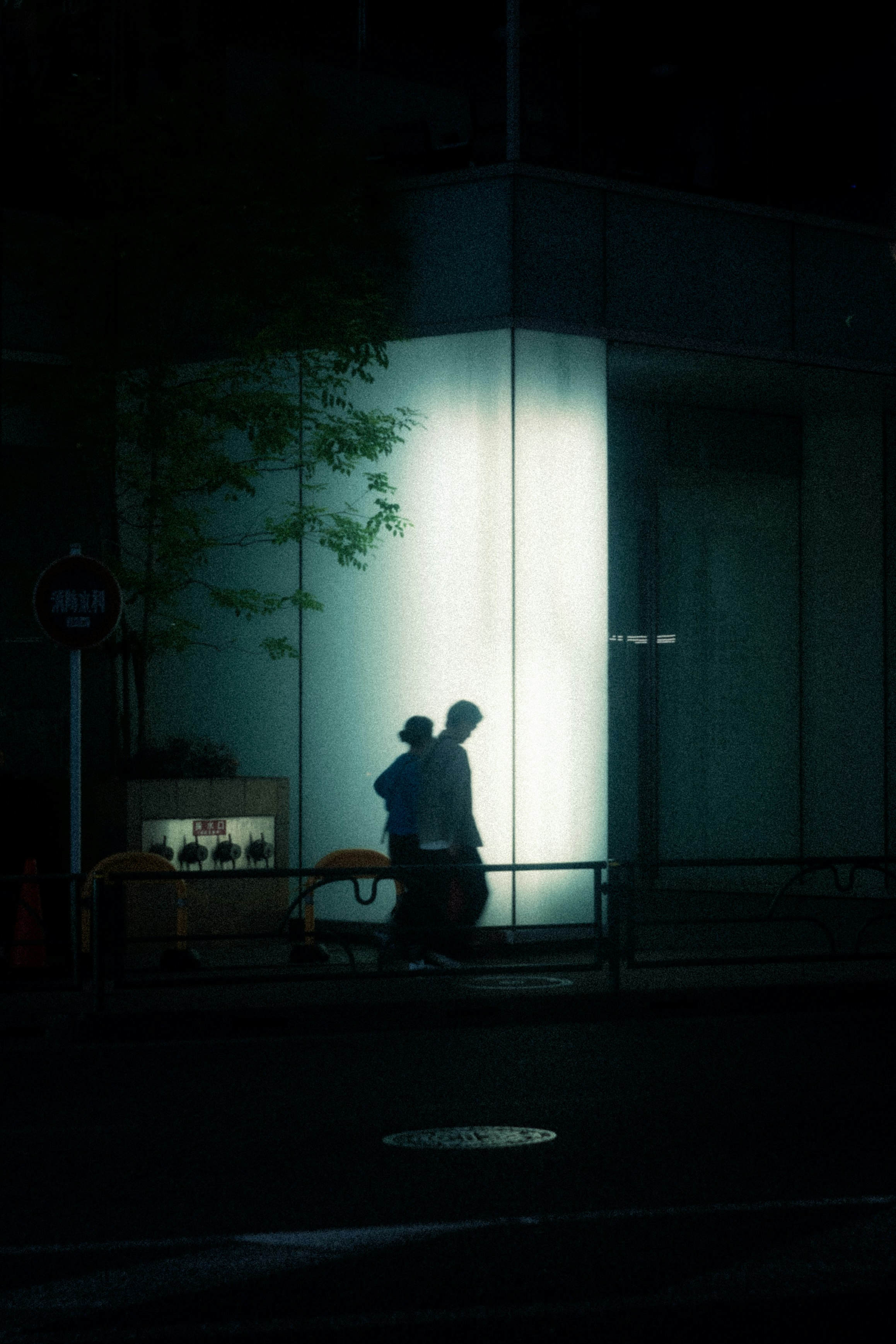 Silueta caminando frente a la entrada de un edificio de noche