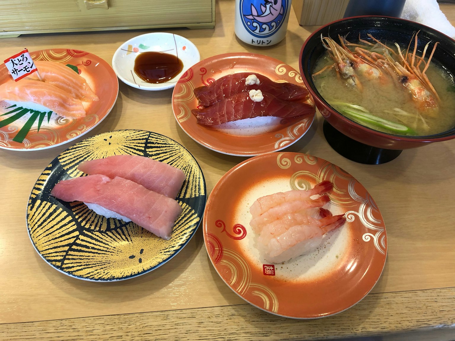 A table setting featuring colorful sushi plates and miso soup