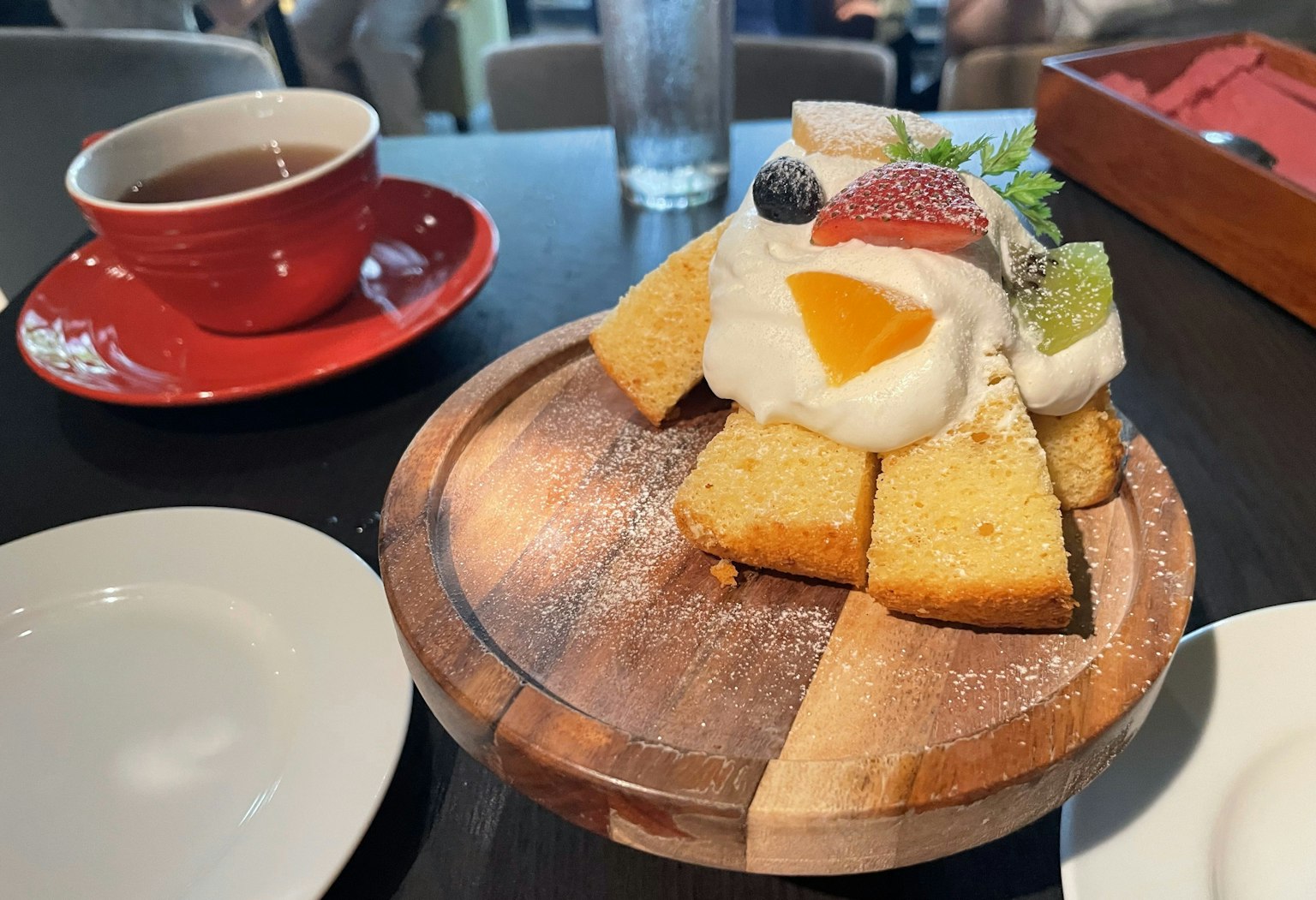 ขนมหวานมีเค้กและผลไม้บนจานไม้ข้างๆ ชา
