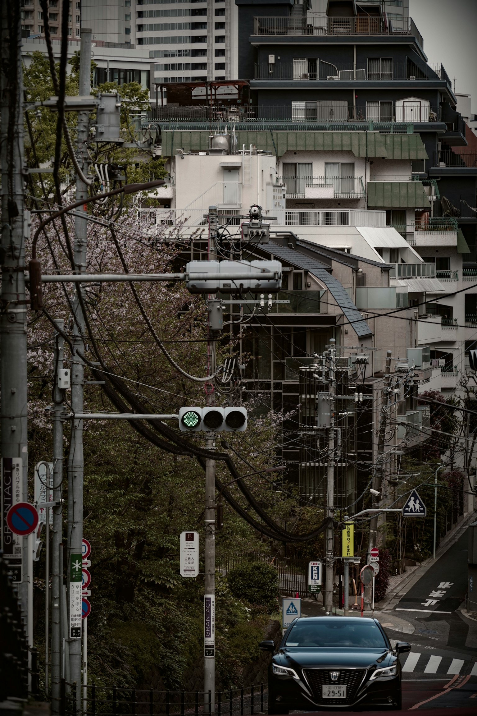 Foto einer Straße in Tokio mit Stromleitungen auf einer abschüssigen Straße und modernen Gebäuden